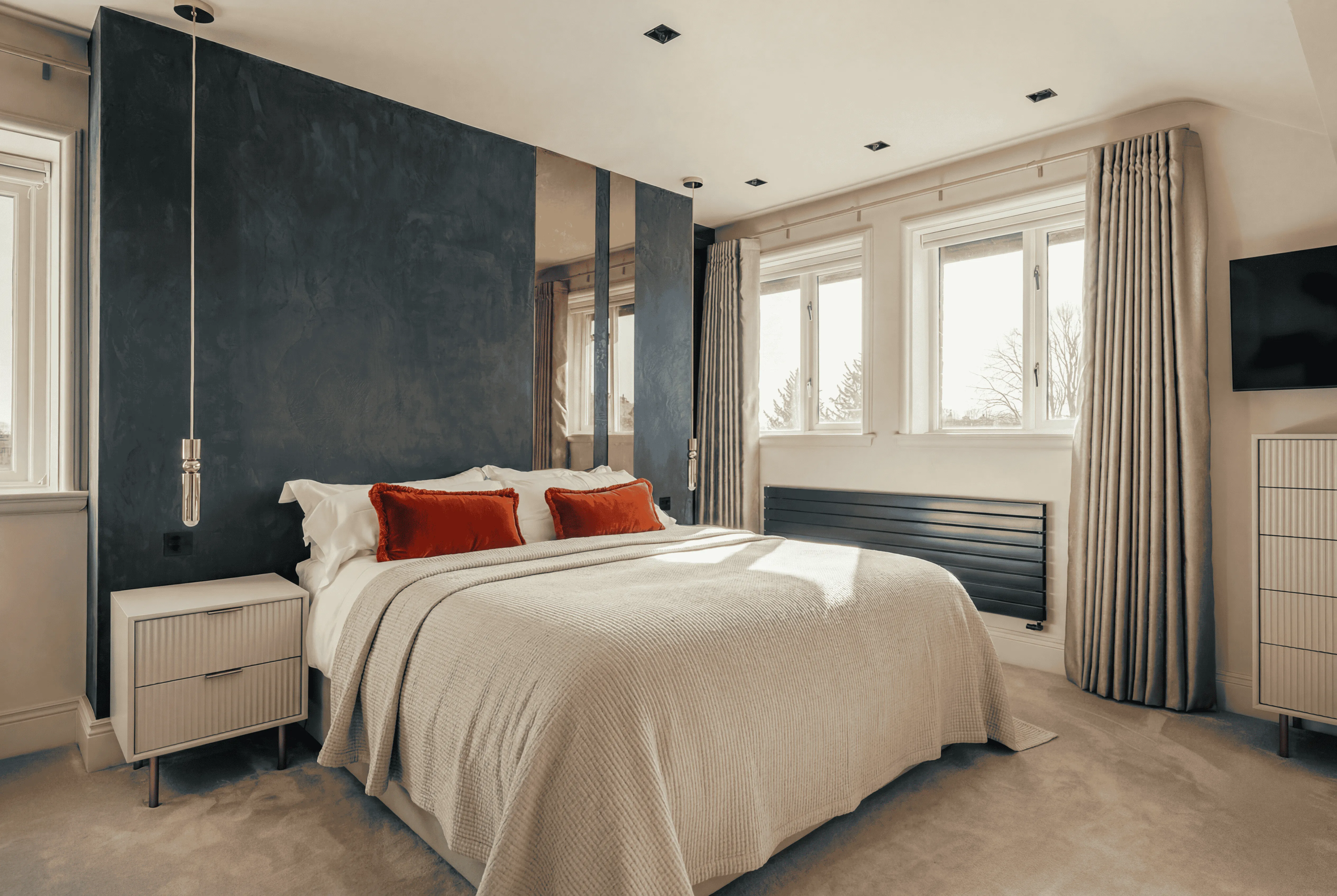 Double bed with orange cushions in a contemporary Harrogate bedroom