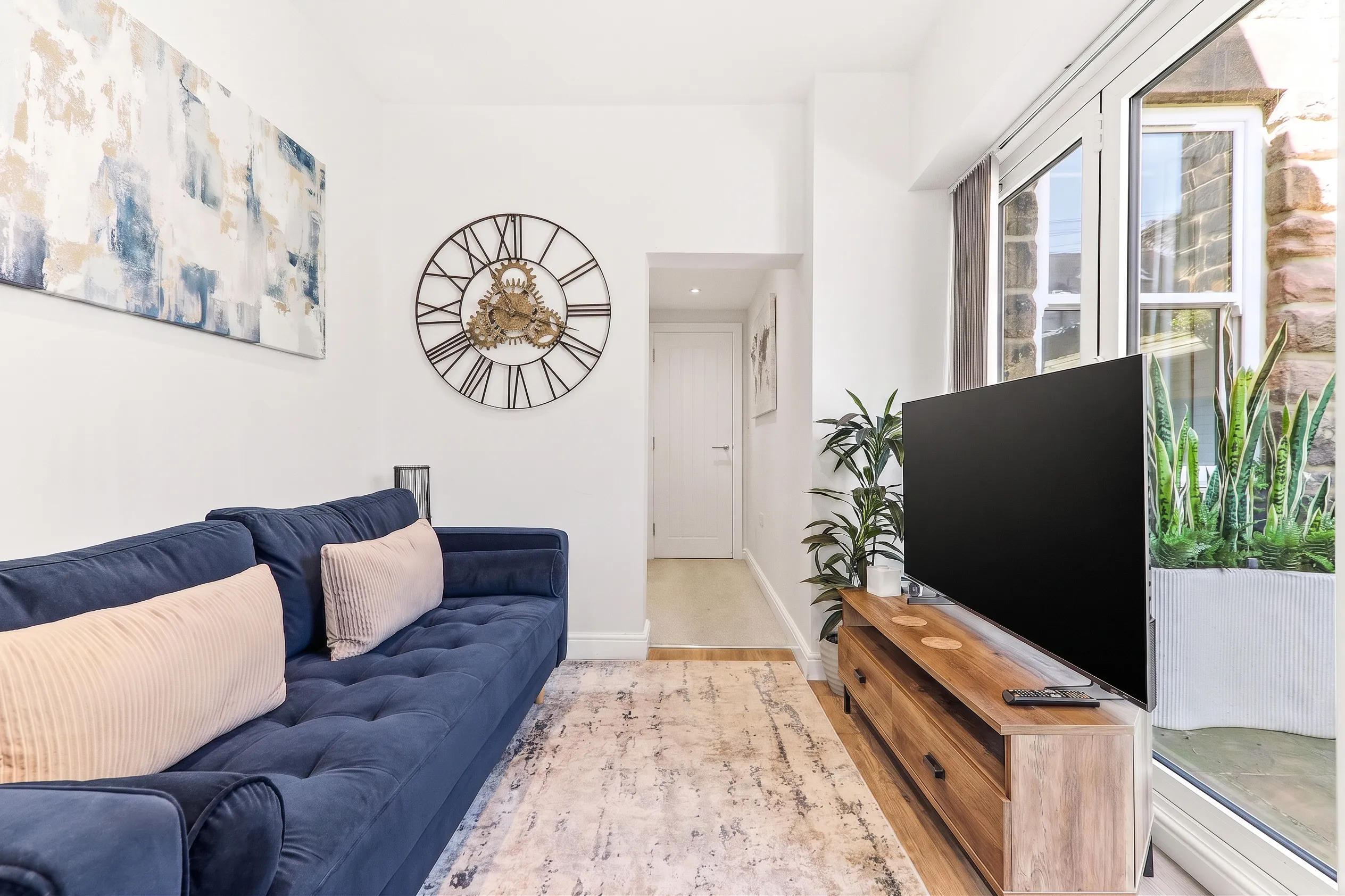Living room with a navy sofa and wall clock in a Harrogate apartment