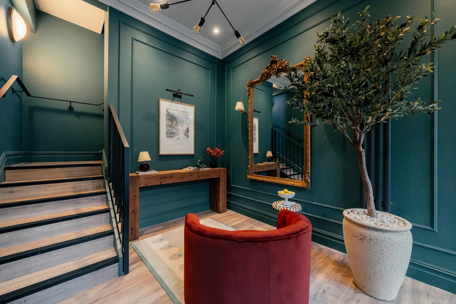 Dark green entrance hall with a gilded mirror and red velvet chair at St James Apartments, Harrogate