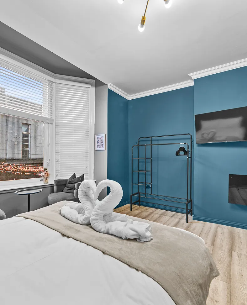 Blue-walled bedroom with towel swans on the bed in a Harrogate studio