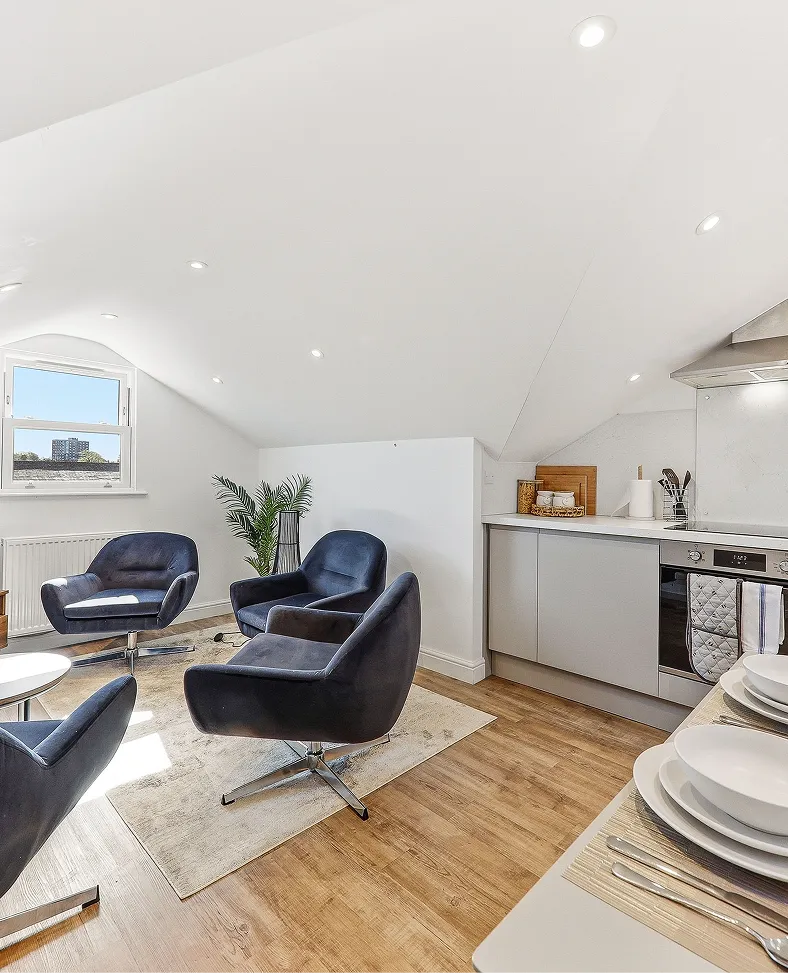 Open-plan loft kitchen and lounge with blue armchairs in a Harrogate apartment