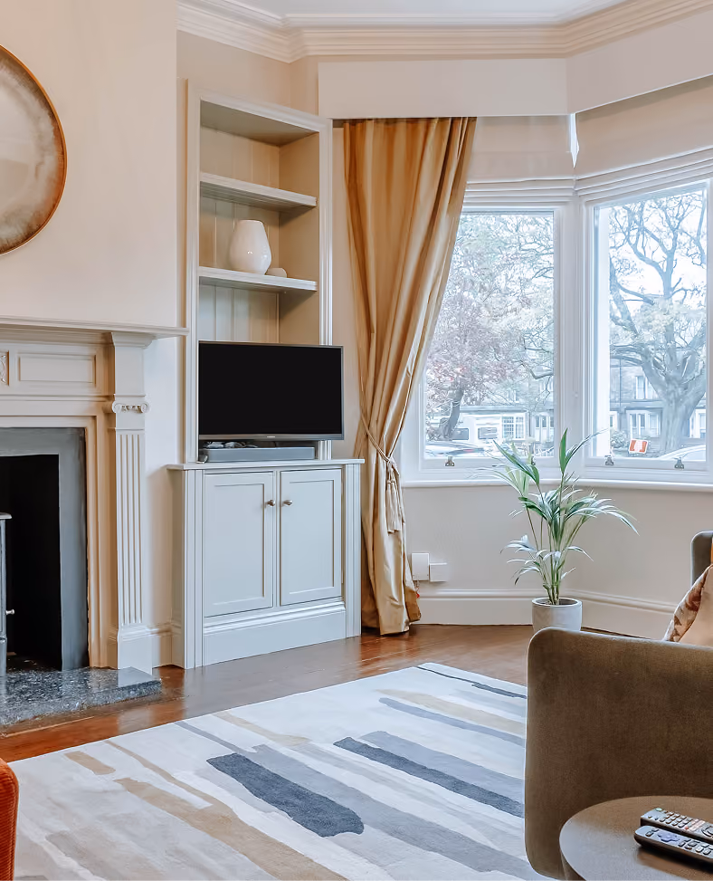 Living room with a period fireplace and bay window in a Harrogate apartment