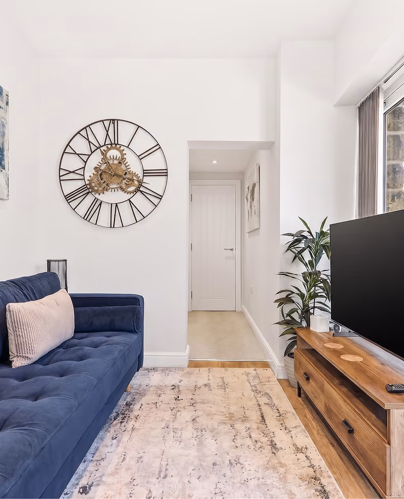 Living area with a navy sofa and large wall clock in a Harrogate apartment
