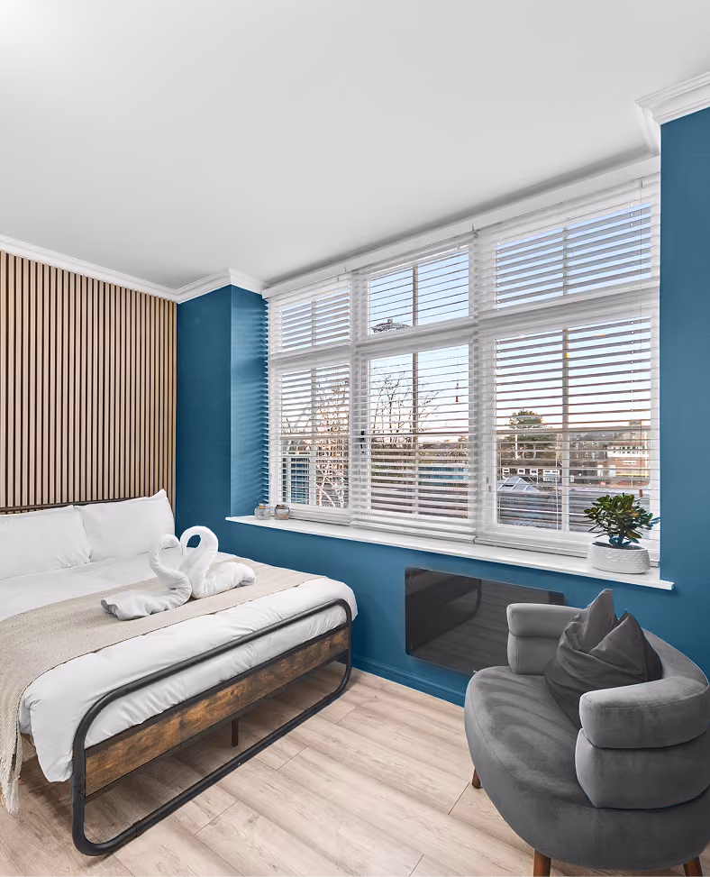 Bedroom with a blue feature wall and shuttered windows in a Harrogate studio