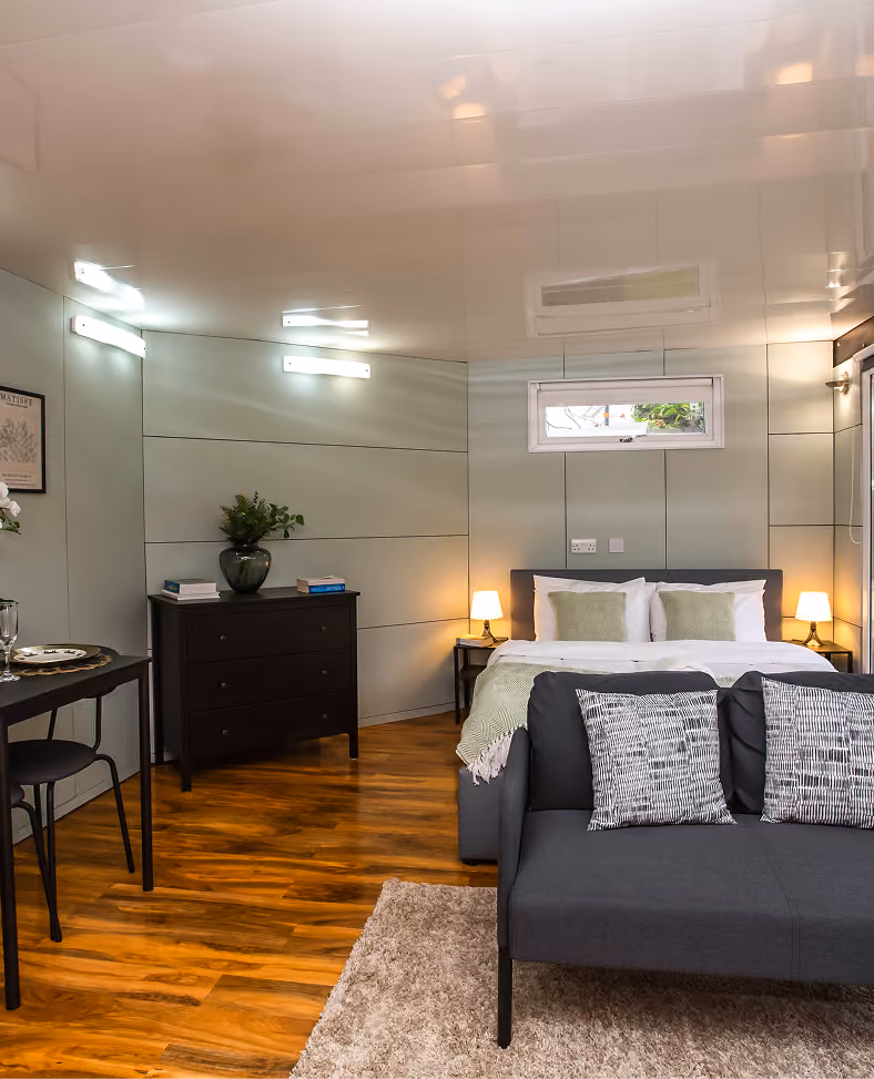 Bedroom with a dark wooden floor and grey bedding in a Harrogate apartment