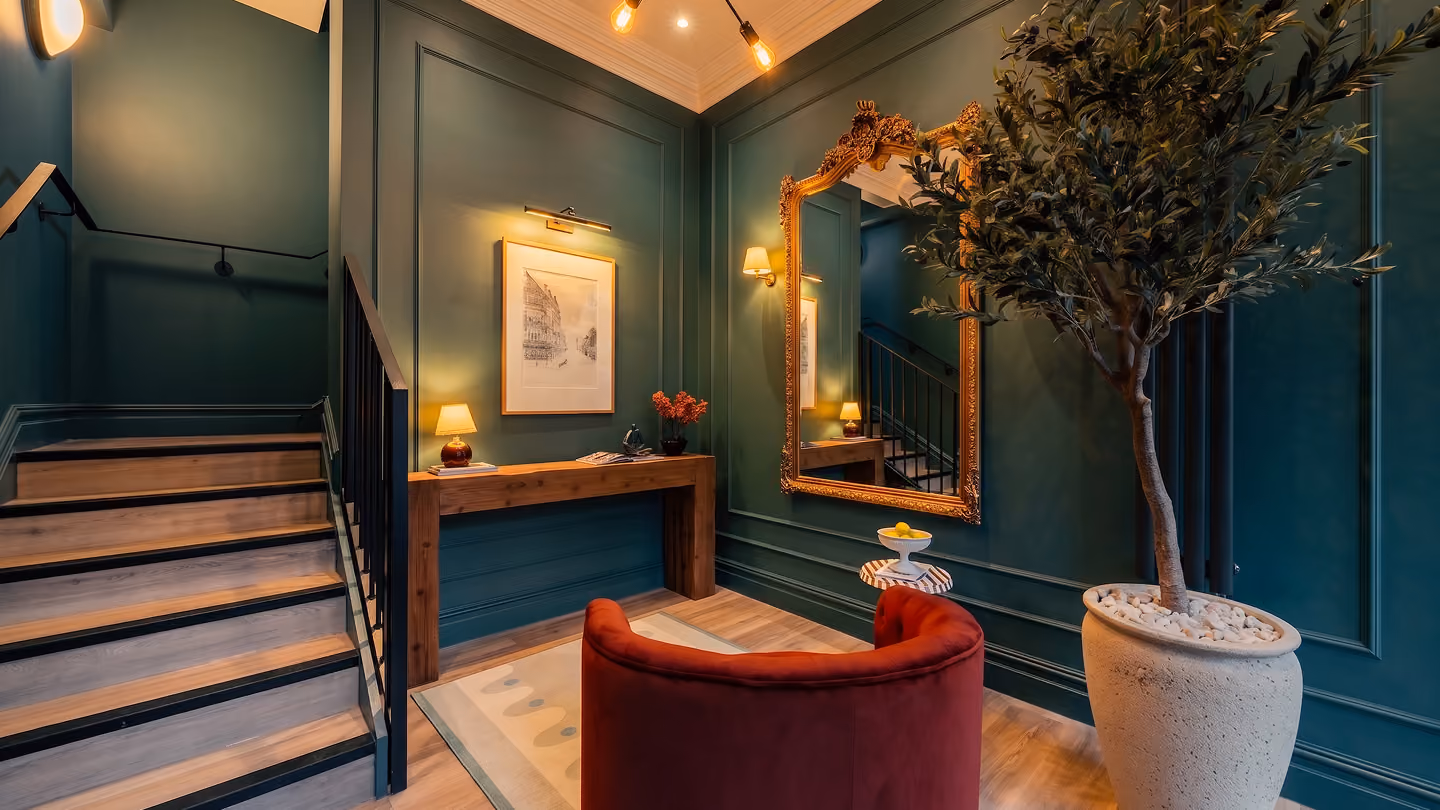 Dark green hallway with a gilded mirror and framed art in a Harrogate apartment