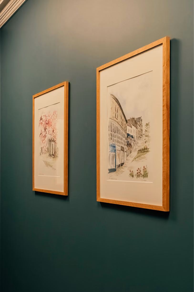 Framed watercolour prints of Harrogate on a dark green wall