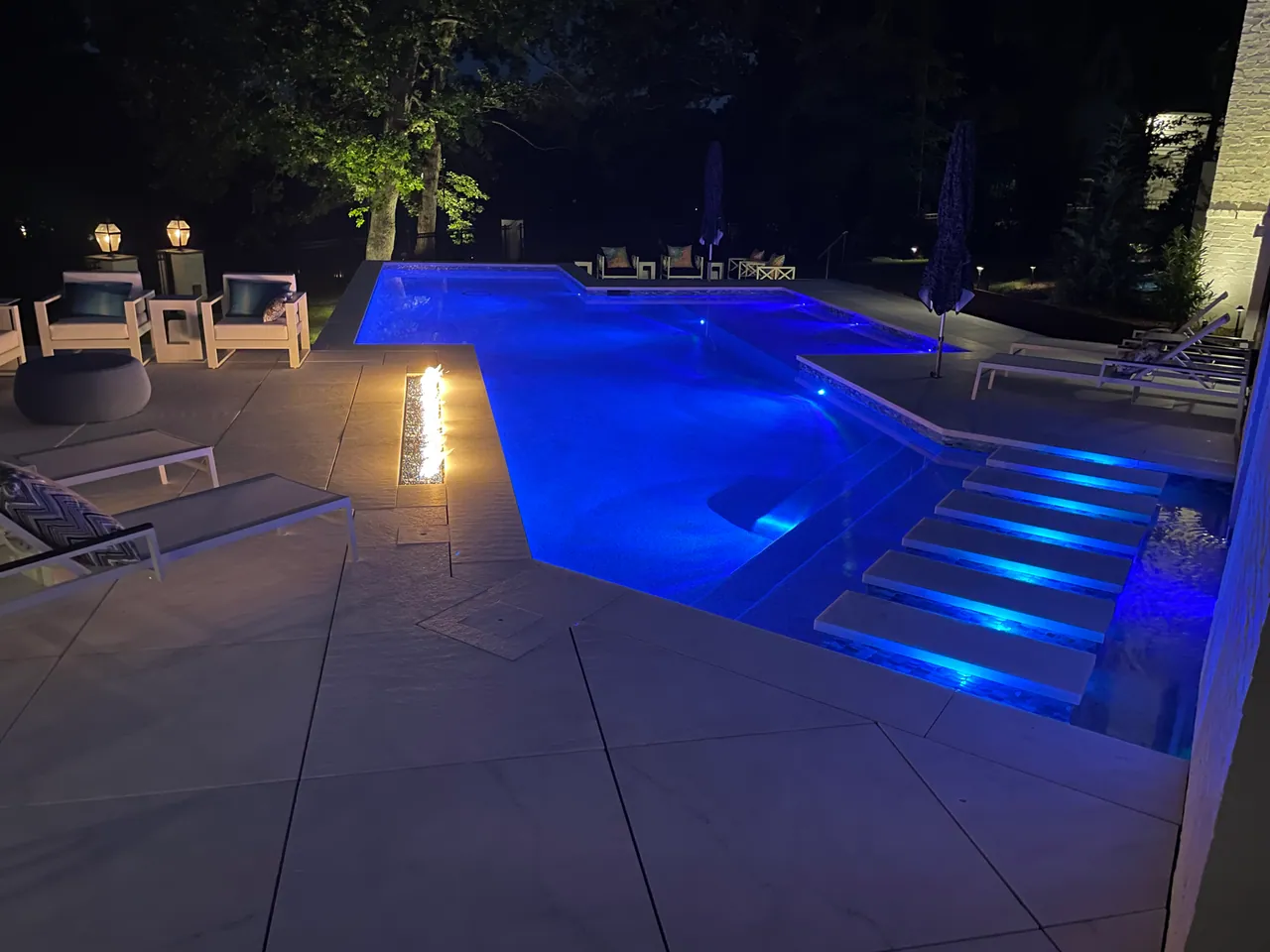 Pool built by Kurt Candler with blue underwater lighting and a fire feature