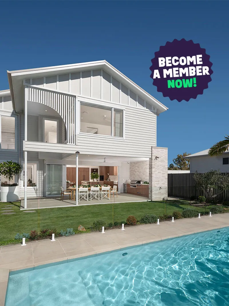 Modern two-story white house with a glass fence around a backyard swimming pool and outdoor dining area under a clear blue sky.