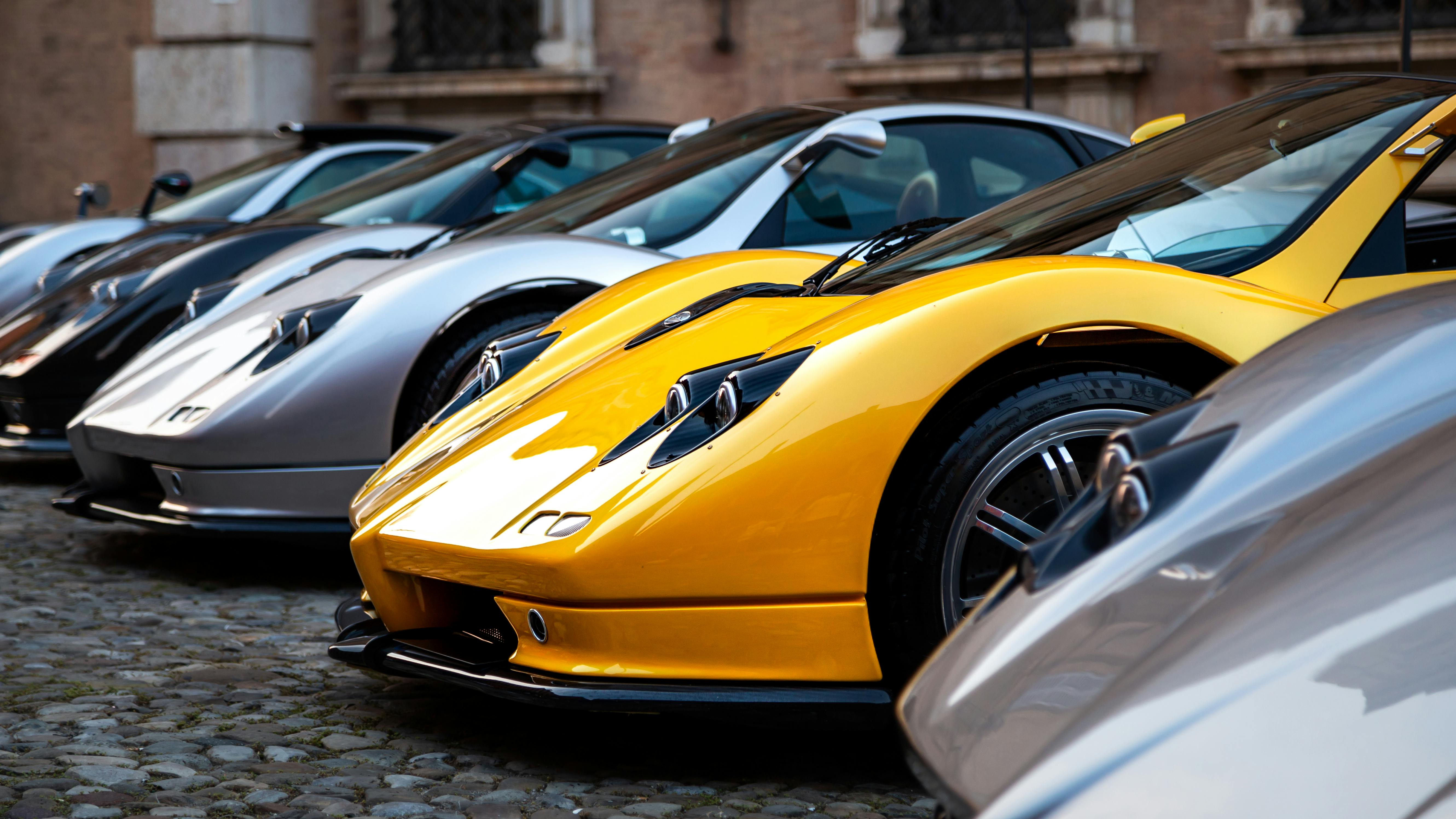 Yellow and silver hypercars lined up on a cobblestone square