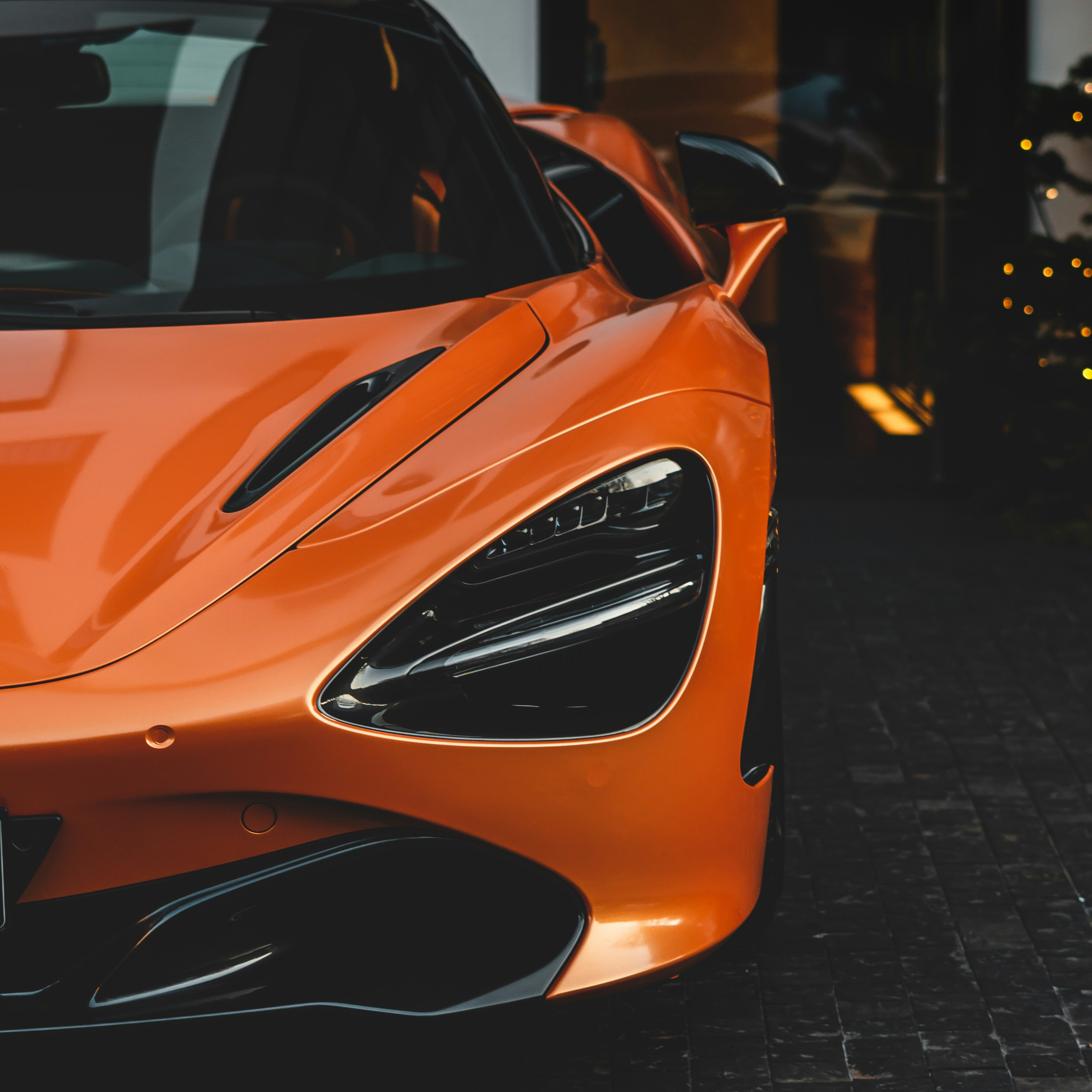 Orange McLaren parked at night outside a lit entrance