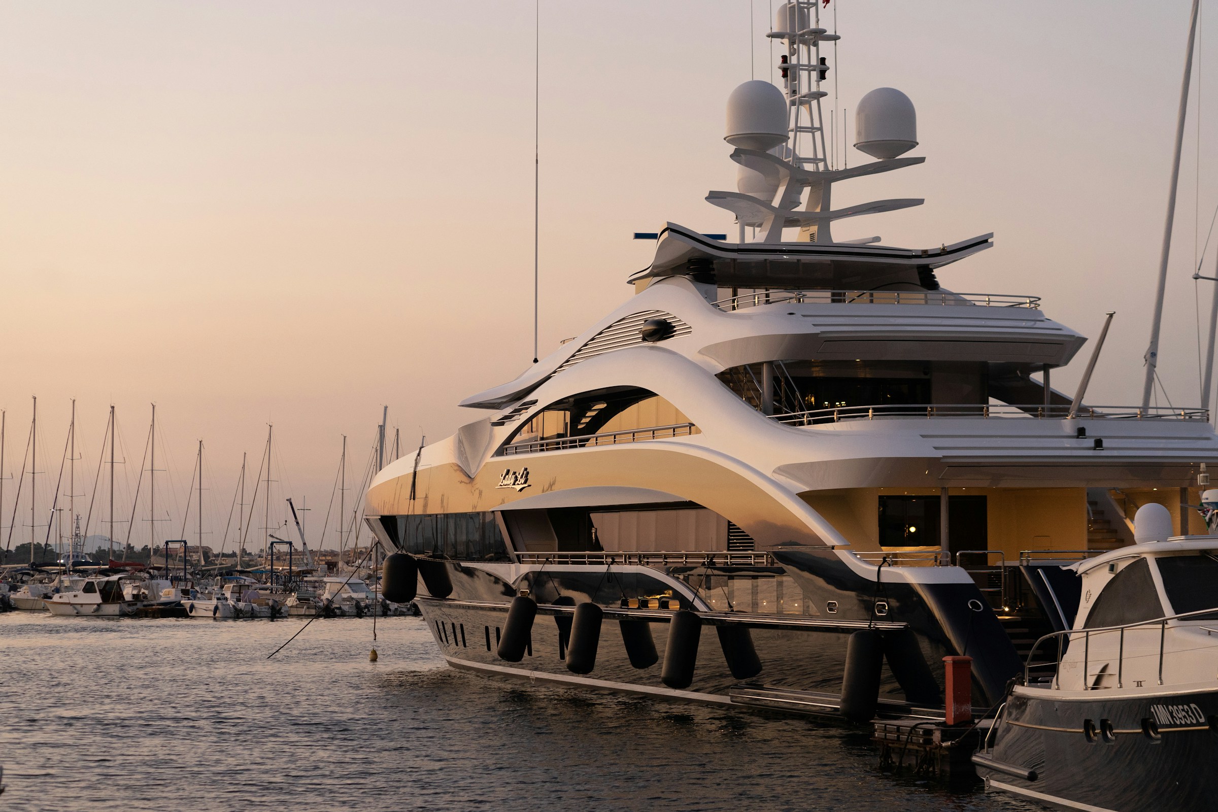 Superyacht docked in a marina at sunset, ready for a private yacht charter
