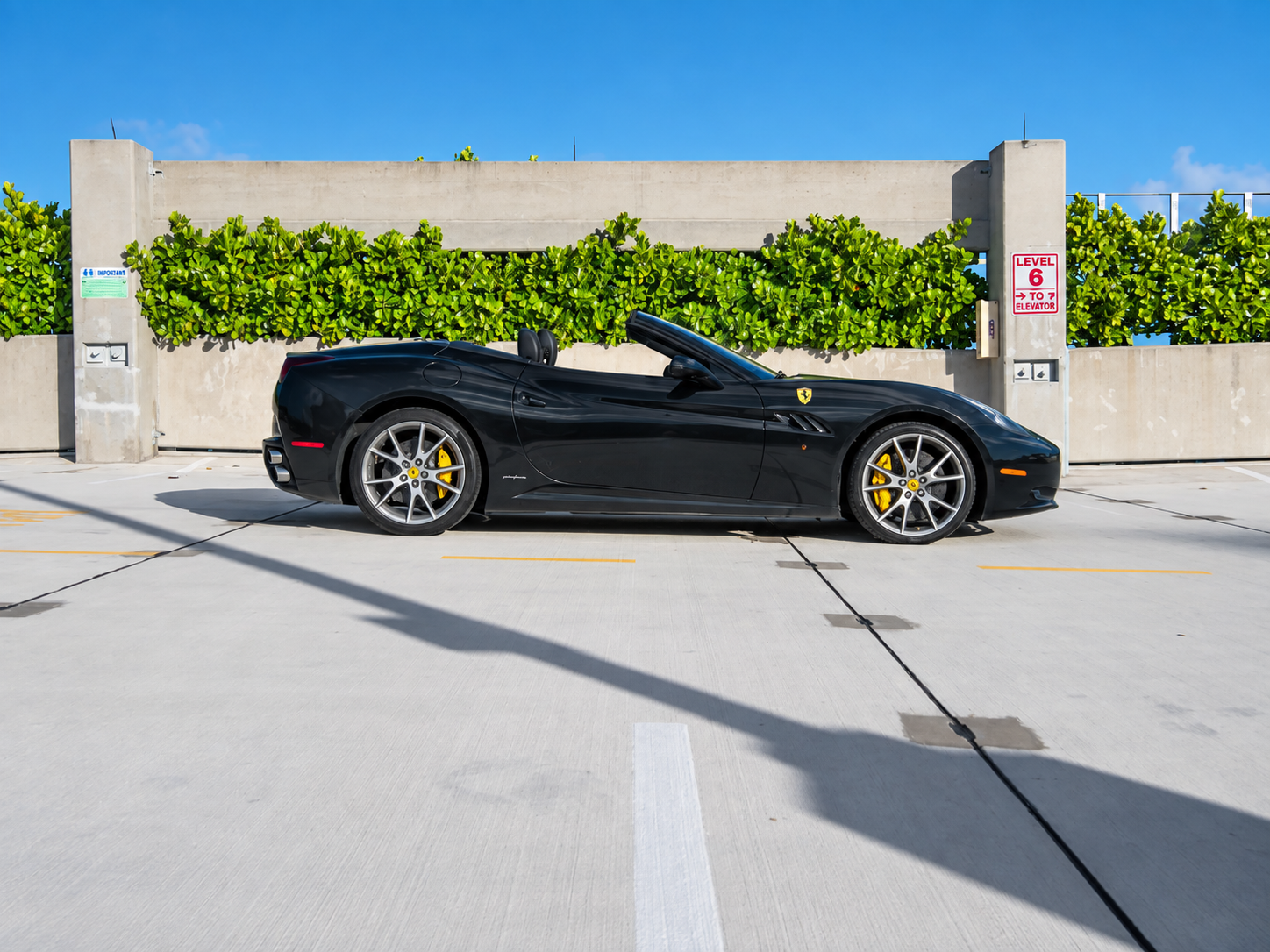 Side view of the black Ferrari California T rental with the top down