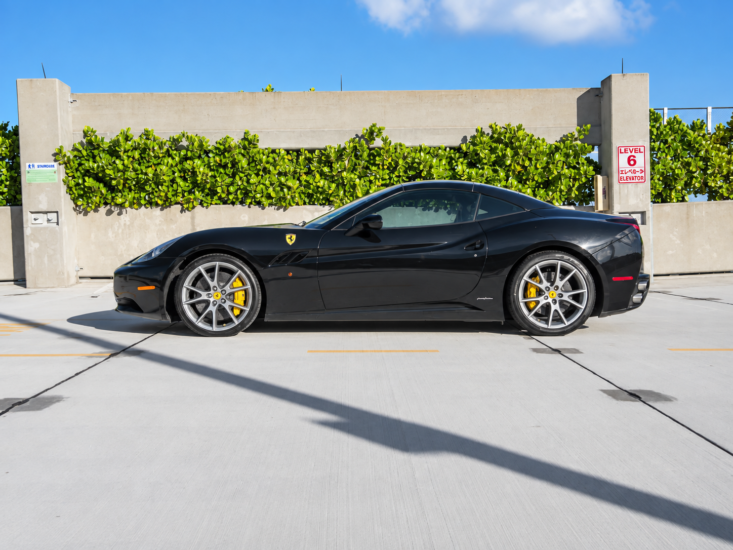 Side view of the black Ferrari California T rental, a 2 door grand tourer