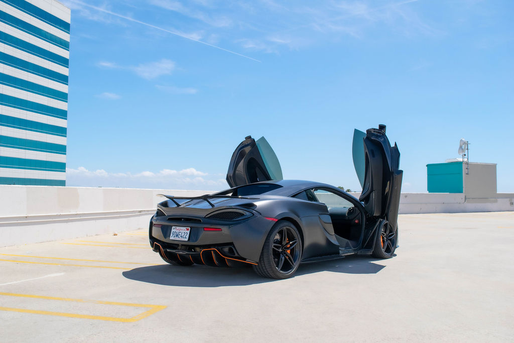 Black McLaren 570S rental, a mid-engine 2 seat supercar with dihedral doors