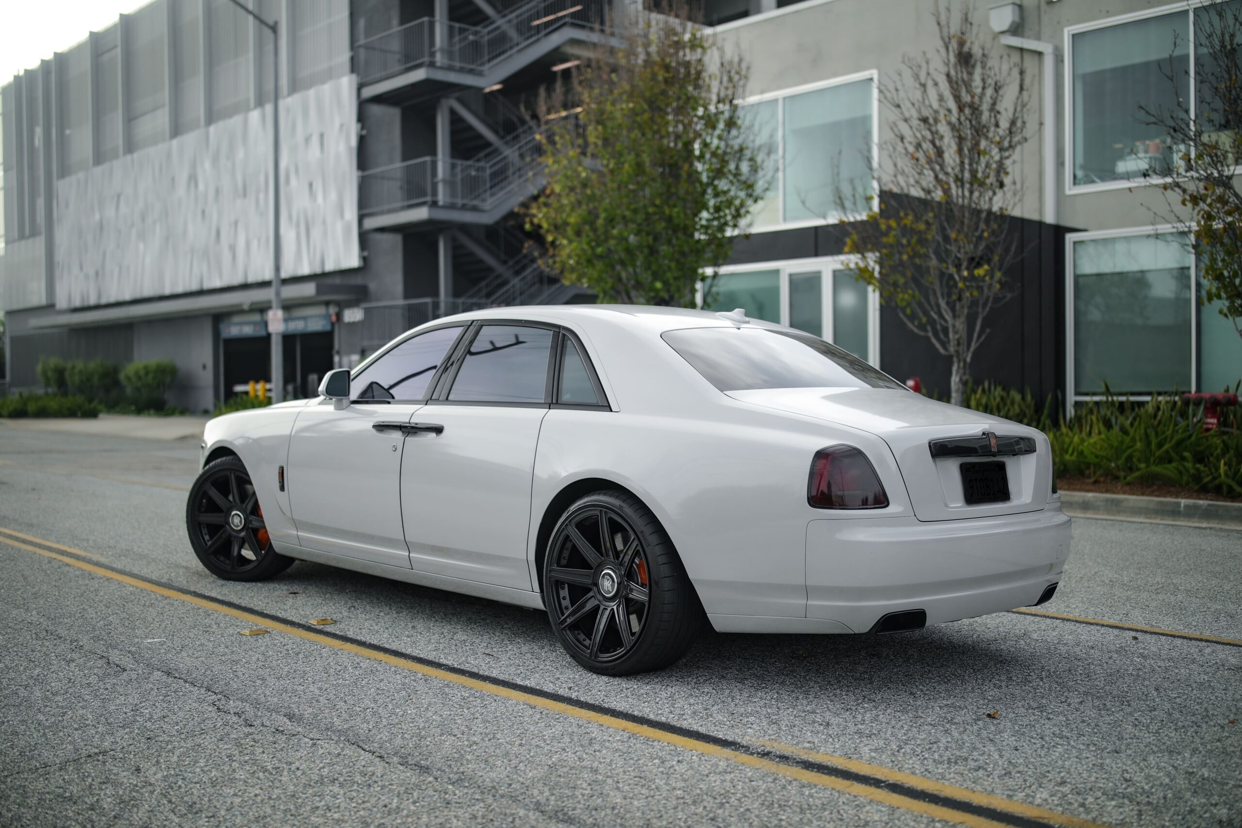 Rear view of the white Rolls Royce Ghost rental, a rear-wheel drive V12 sedan