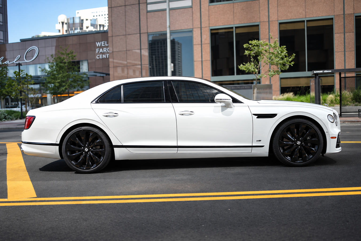 Side view of the white Bentley Flying Spur rental, a 4 door luxury sedan