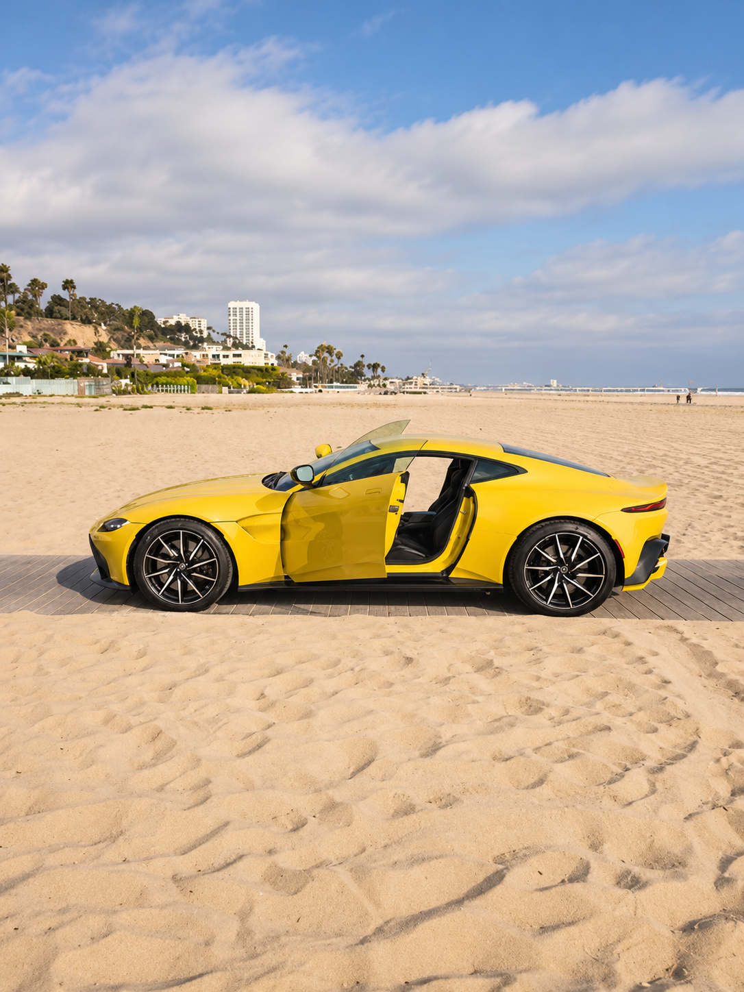 Side view of the yellow Aston Martin Vantage rental with the door open