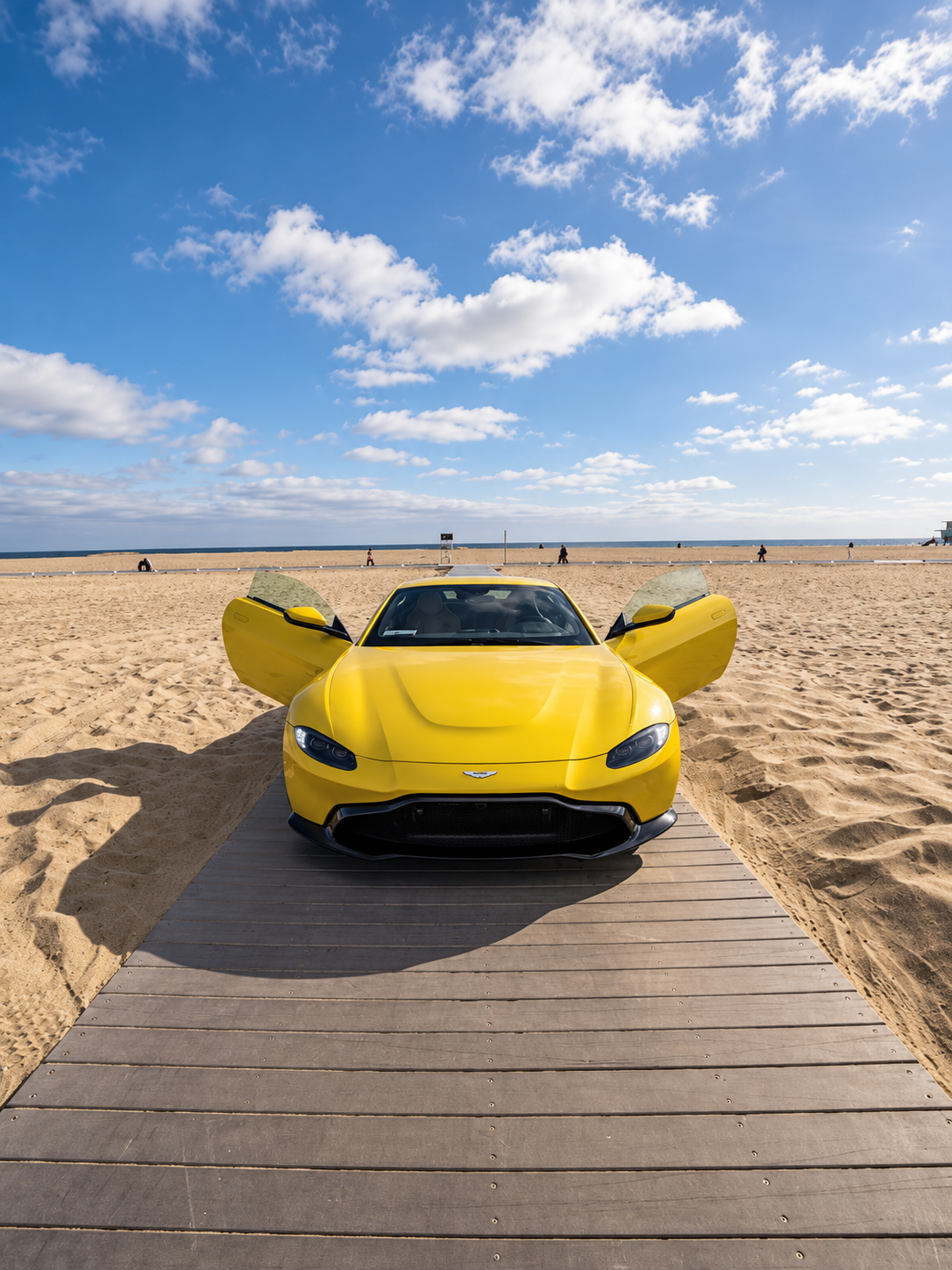 Front view of the yellow Aston Martin Vantage rental with the doors open
