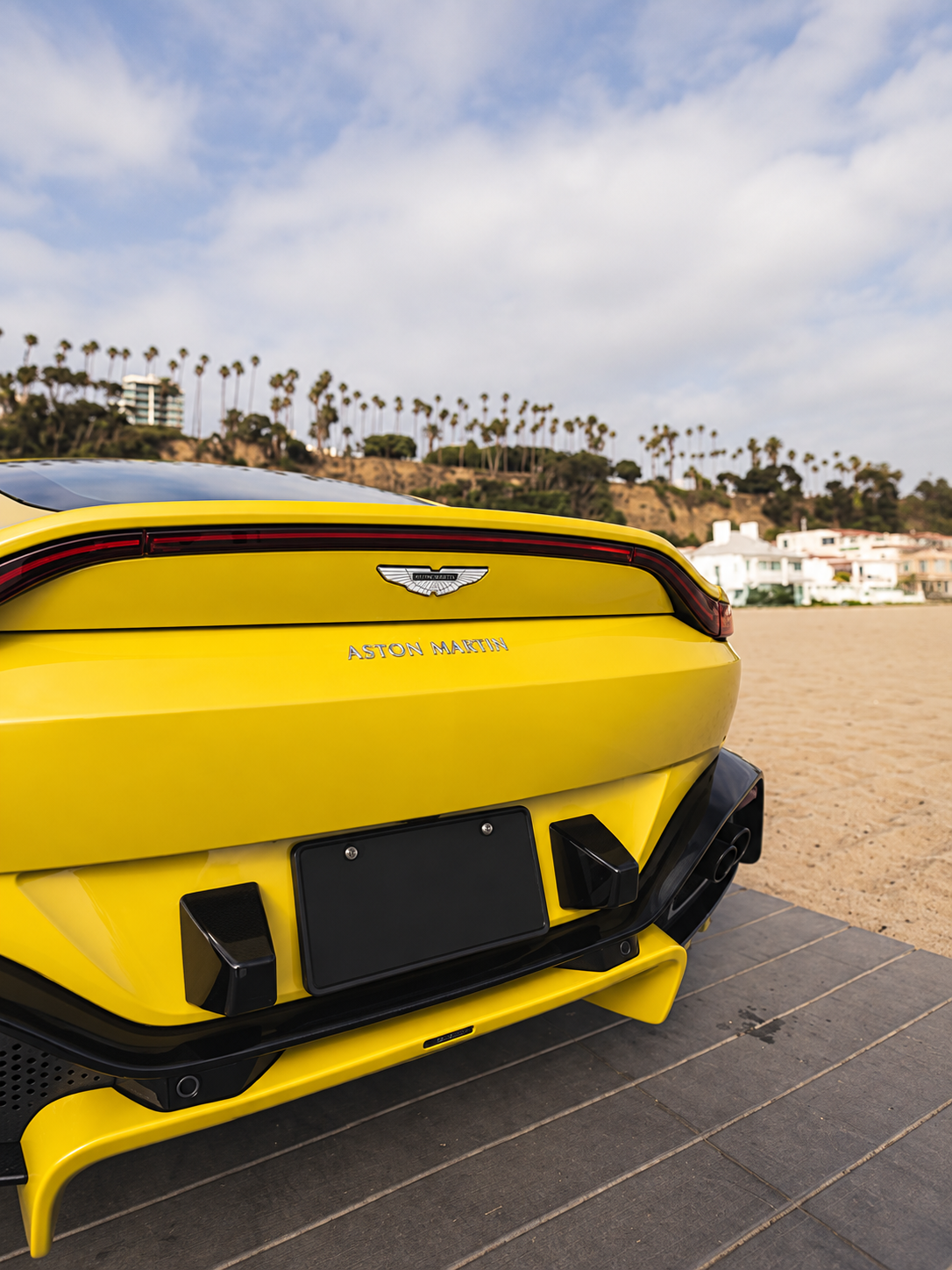 Rear view of the Aston Martin Vantage rental in yellow, 195 mph top speed