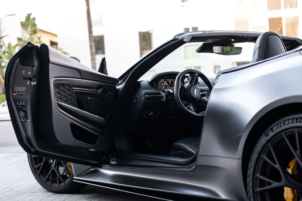 Door open on the grey Aston Martin DB12 Volante rental