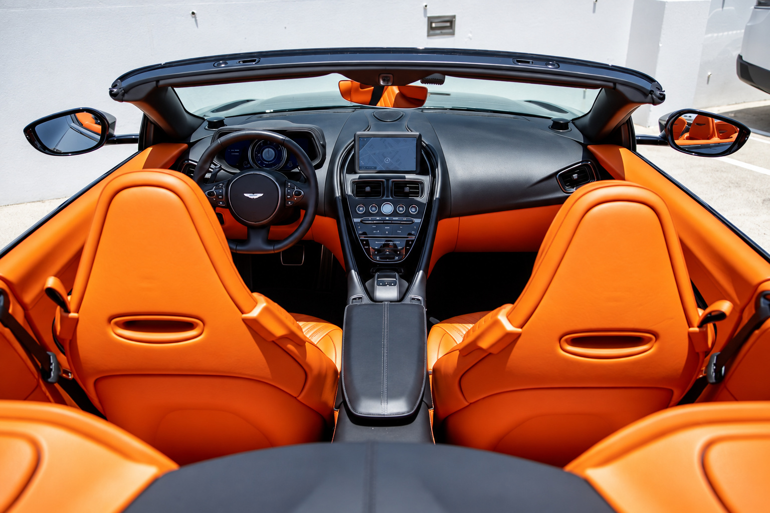 Looking down into the open Aston Martin DB11 Volante cabin, orange seats, orange door cards and a black centre console