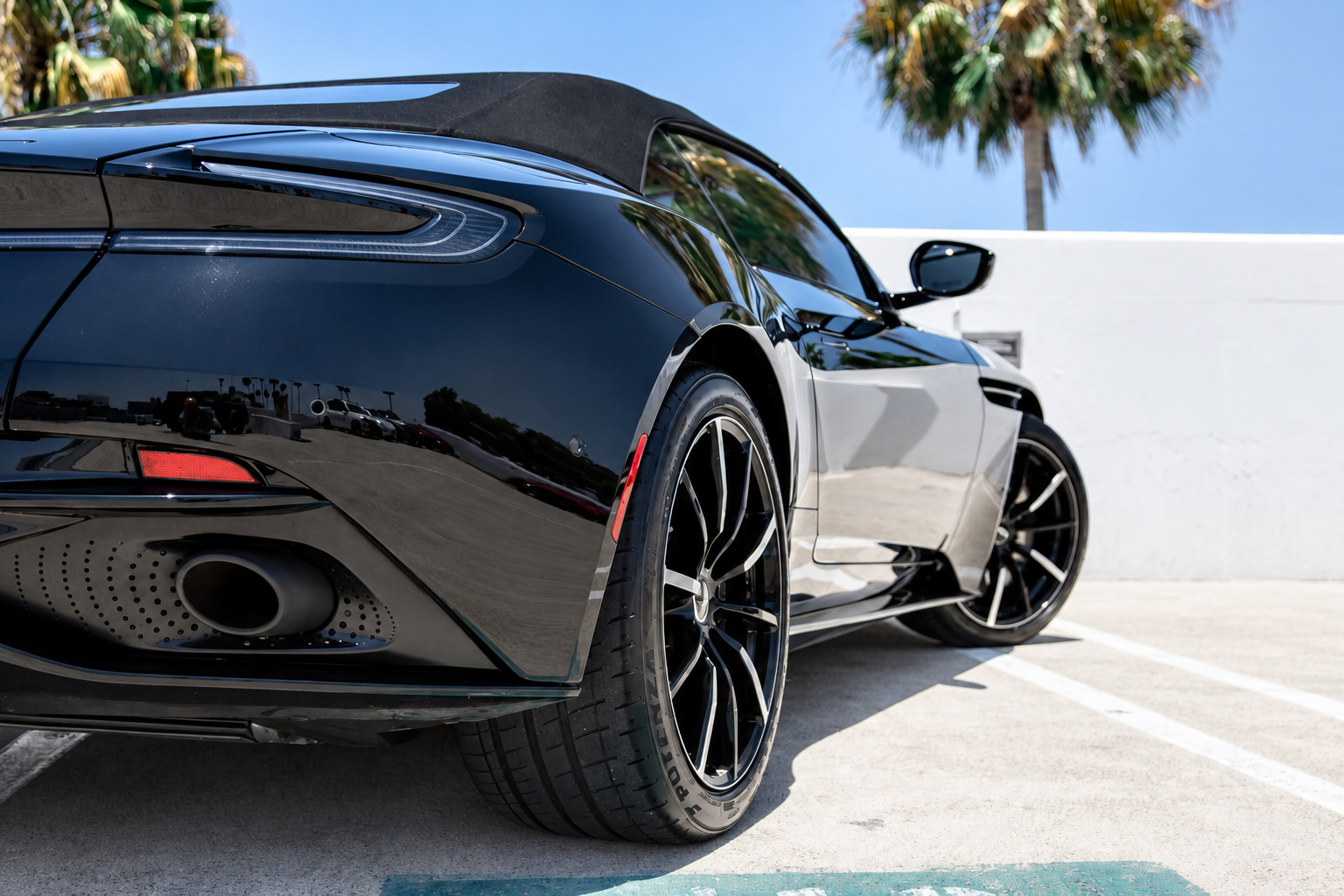Rear quarter detail of the black Aston Martin DB11 Volante, tail light, exhaust tip and black diamond-cut wheel