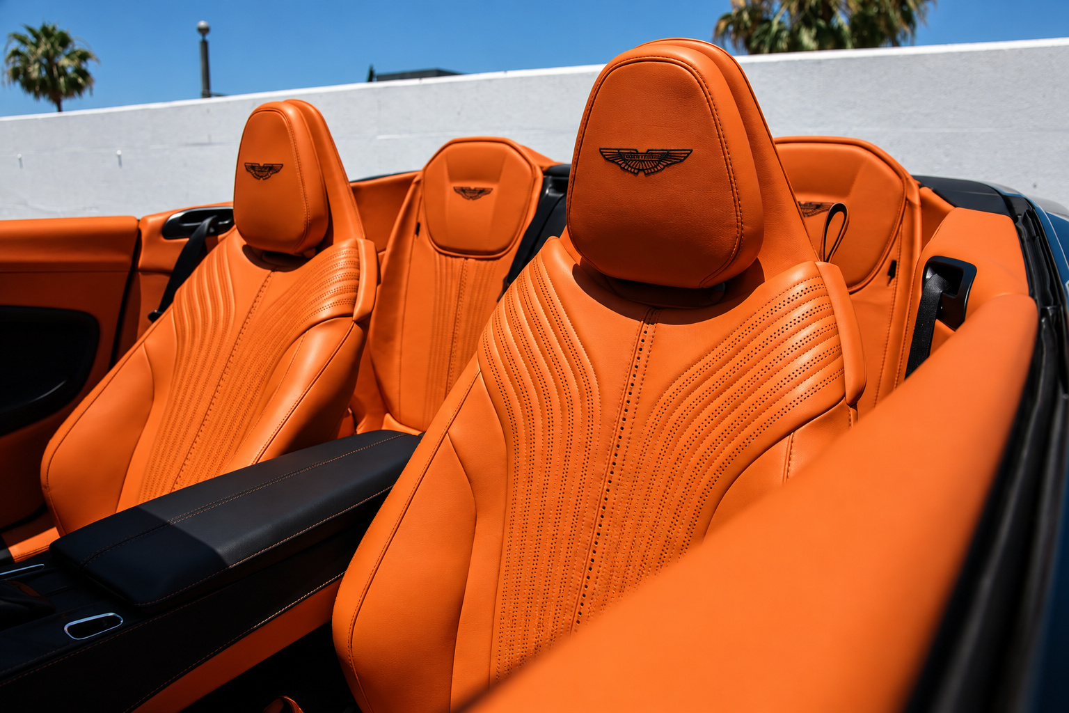 Orange leather seats of the black Aston Martin DB11 Volante from above, wings embroidered into each headrest