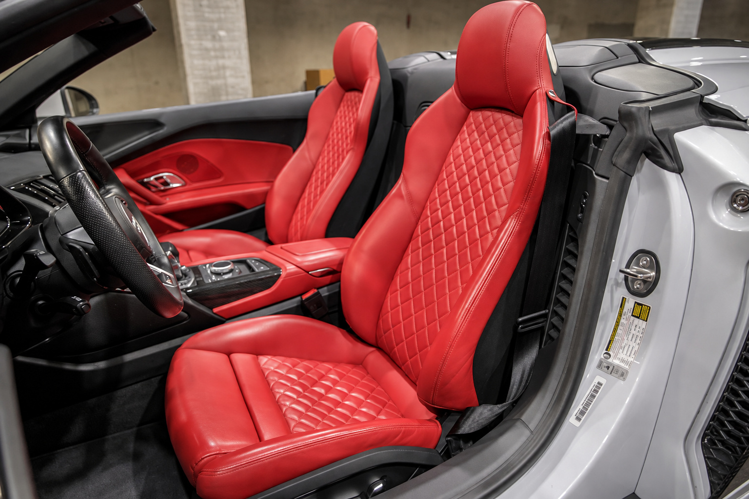 Red diamond-quilted sport seats of the white R8 V10 Spyder seen from above with the roof folded
