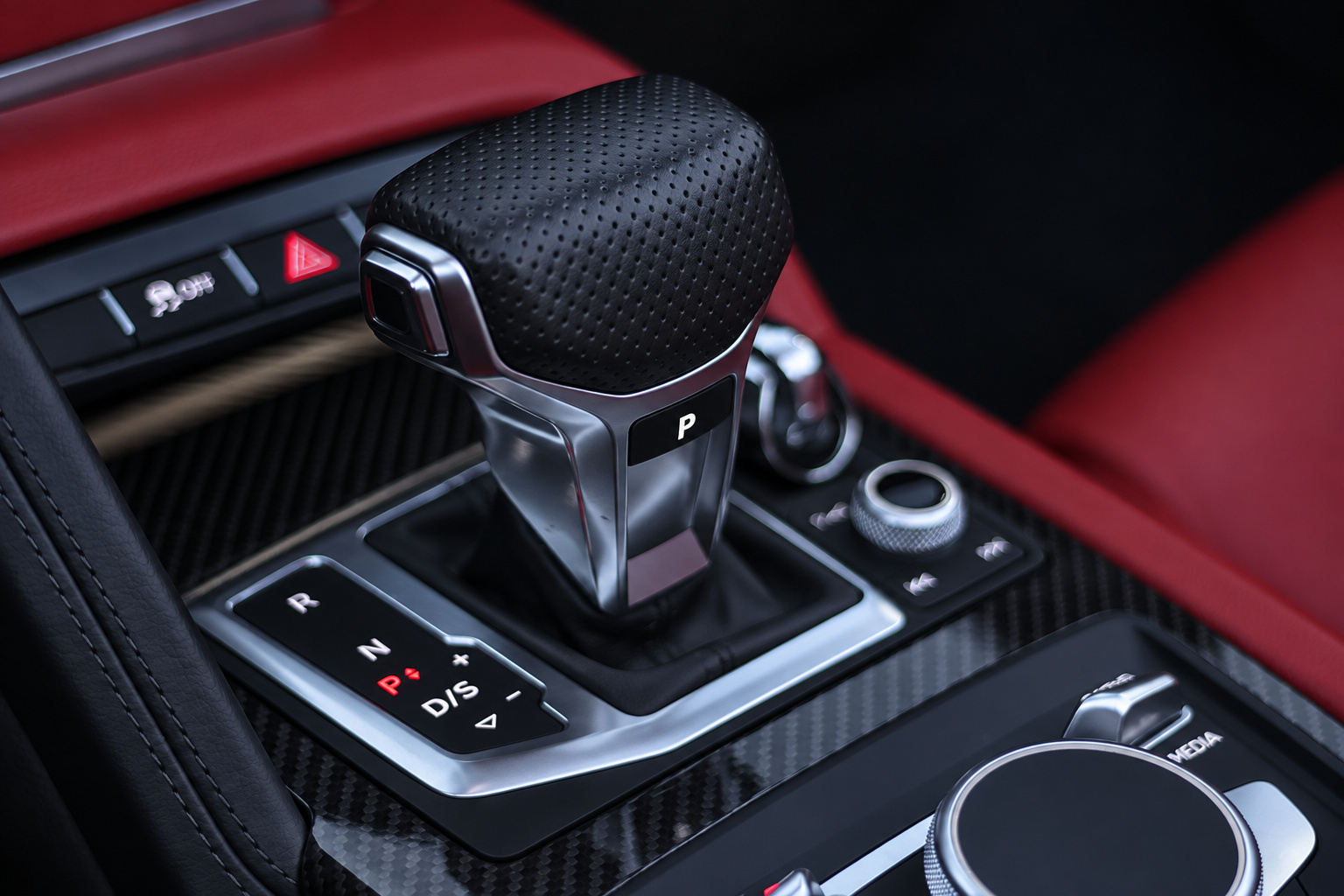 Close-up of the R8 Spyder gear selector and carbon fibre console trim with red leather alongside