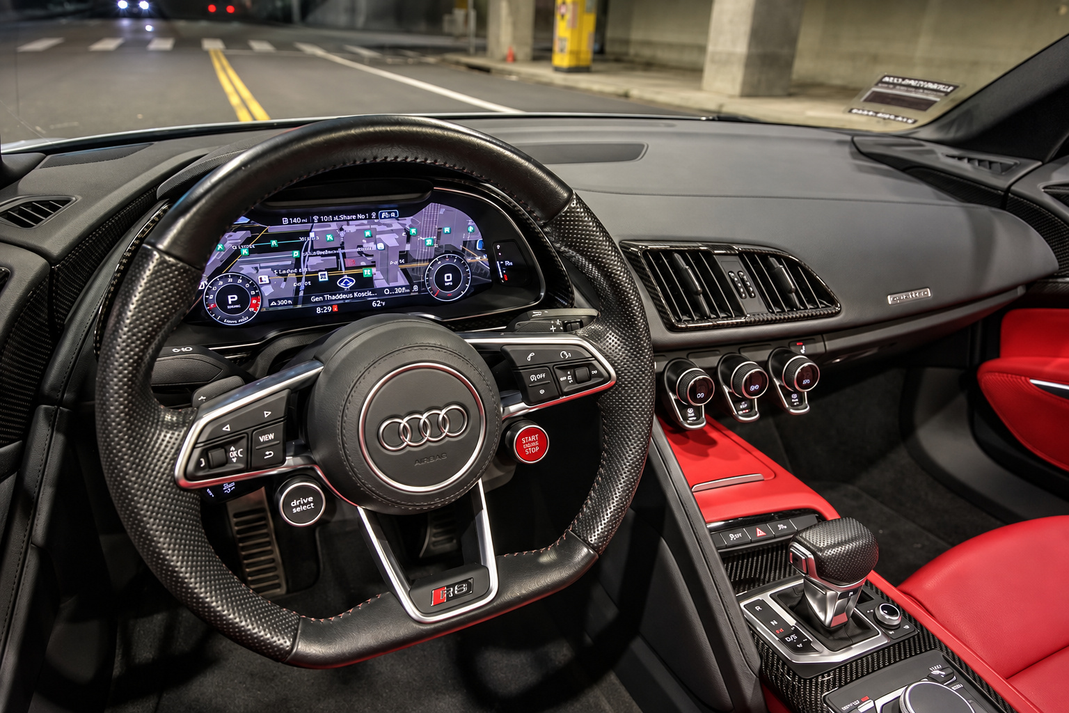 Driver's view of the R8 Spyder cabin, flat-bottom wheel, digital cluster and red leather door panel