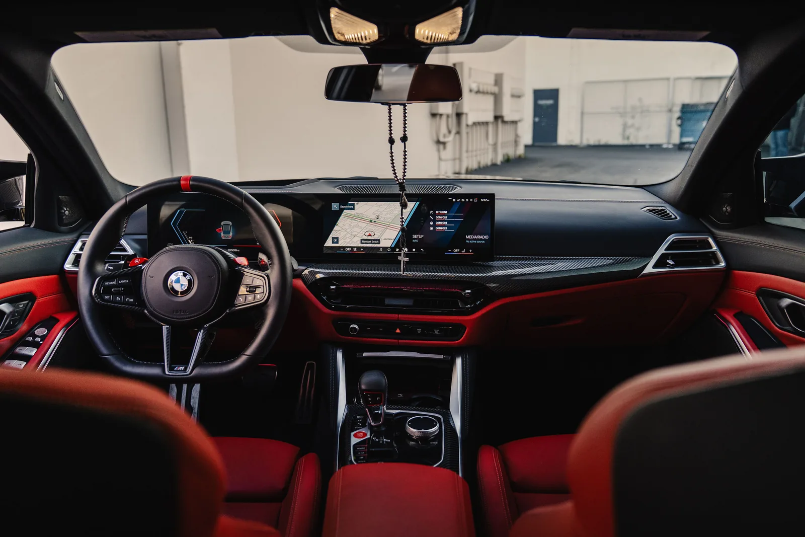 M3 Competition cabin with red leather seats, the curved display and the red marker on the steering wheel