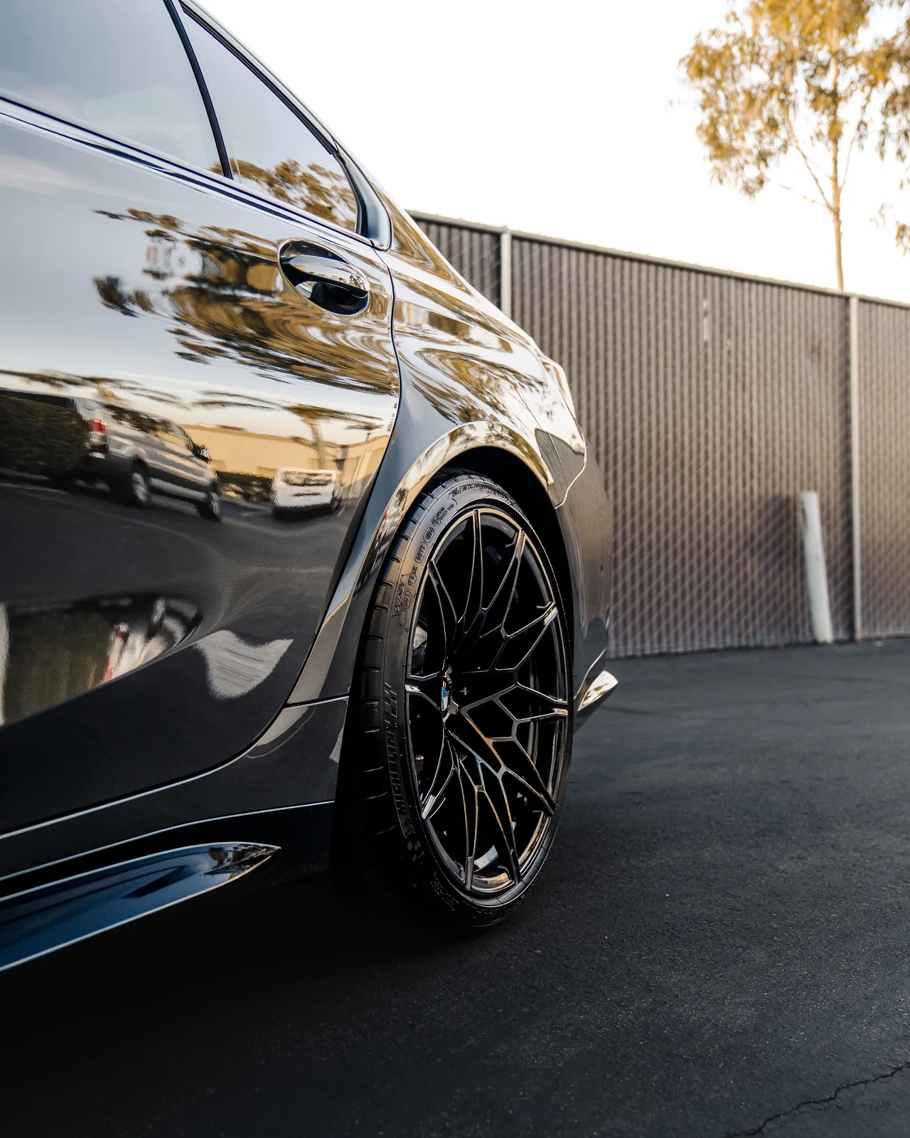 Close-up of the gloss black wheel and front fender of the dark grey M3 Competition xDrive