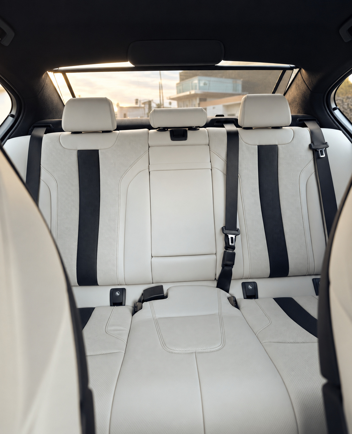 Ivory white rear seats of the BMW M5 Competition with dark seat belts and the centre armrest