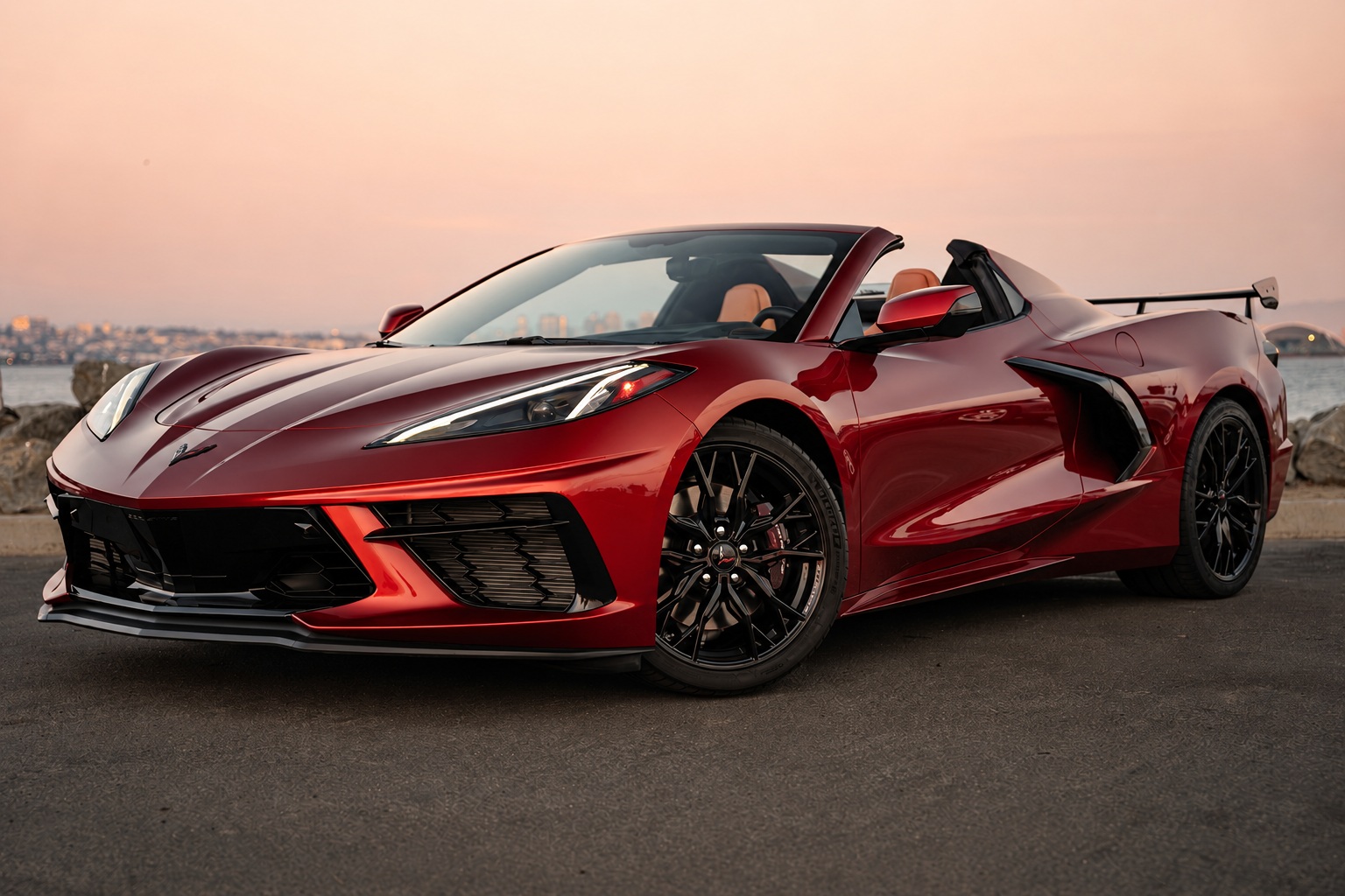 Red Corvette C8 Stingray Convertible, top down, front three-quarter view on the San Diego bayfront at sunset