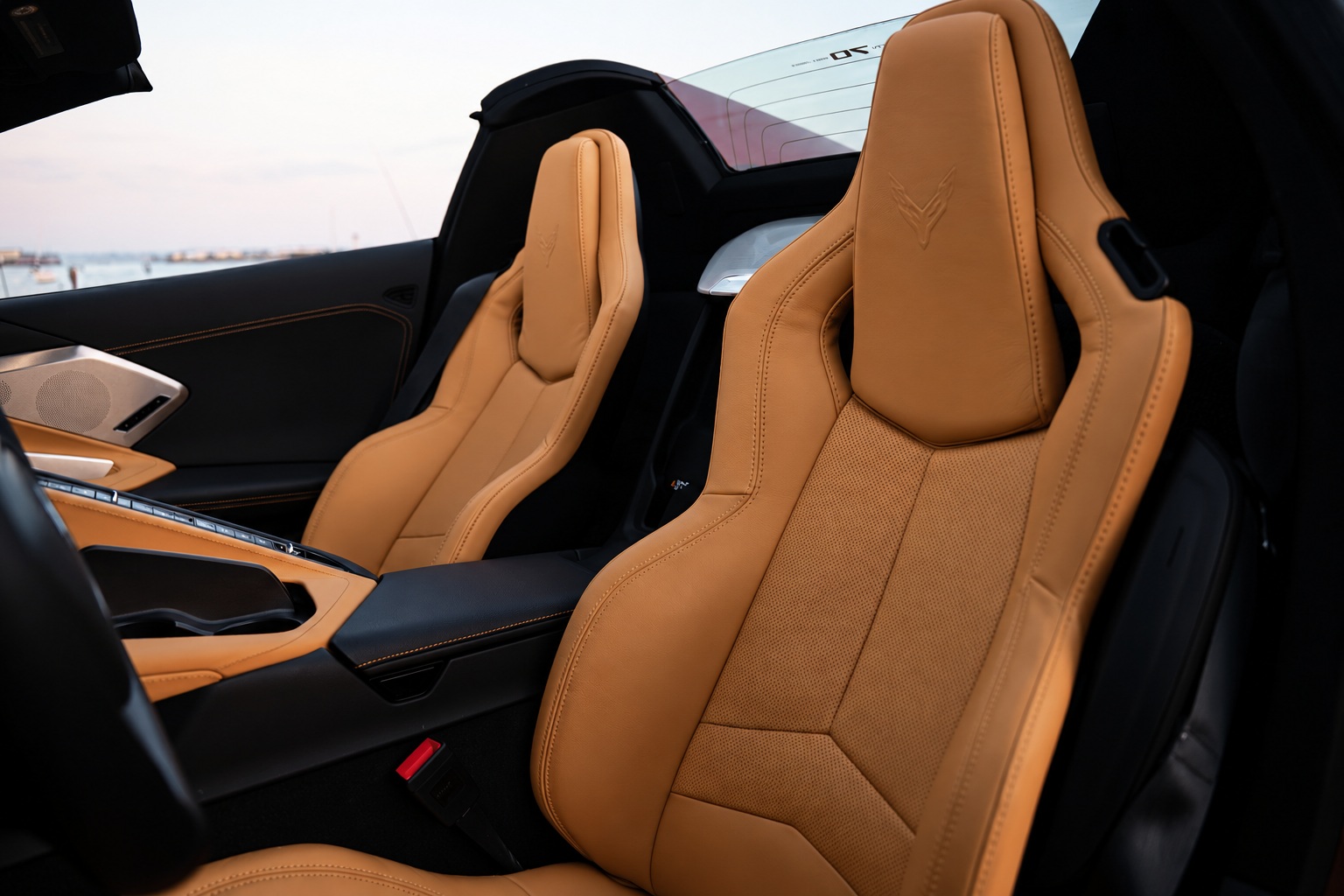 Tan leather seats of the Corvette C8 Stingray Convertible with the flag badge on the headrests, top down