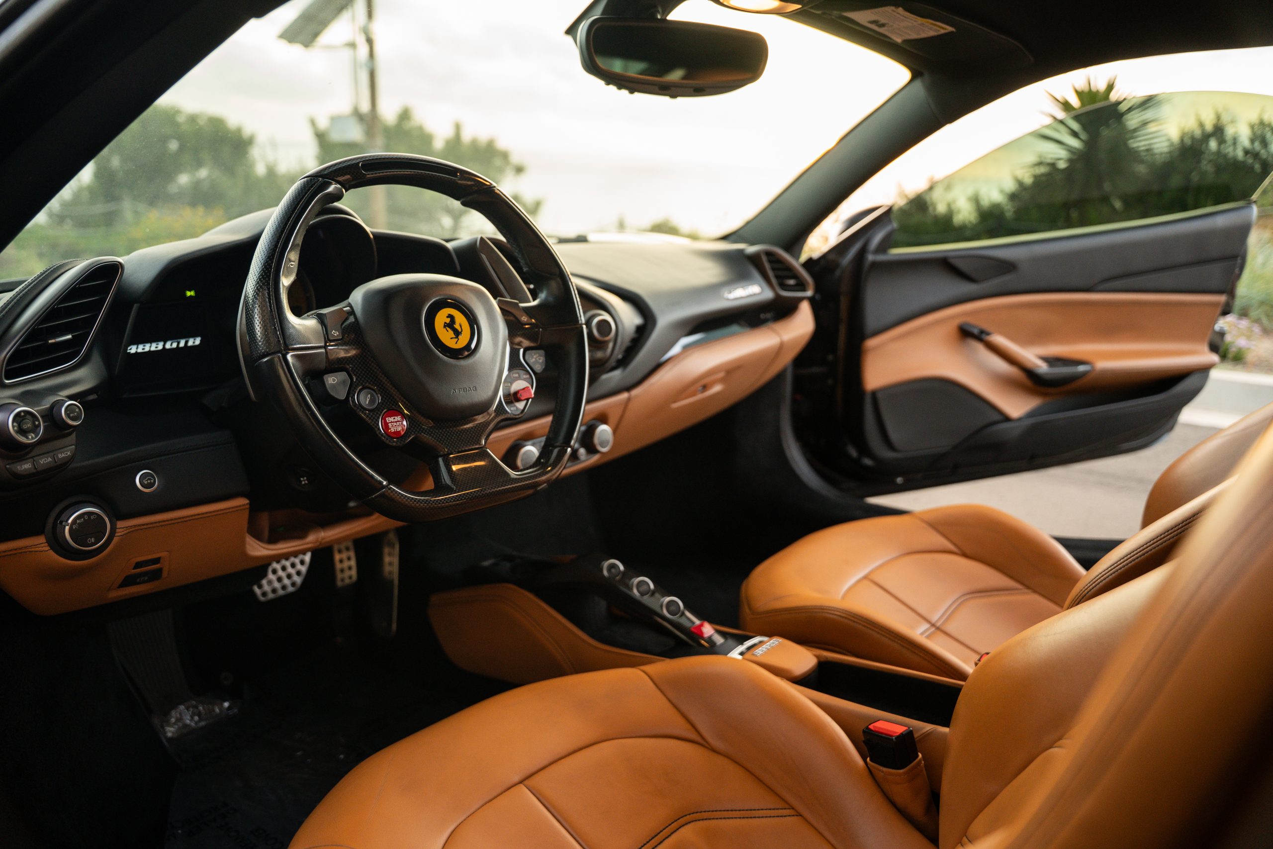Driver's view of the 488 GTB cabin, tan leather, the manettino and yellow shield on the steering wheel