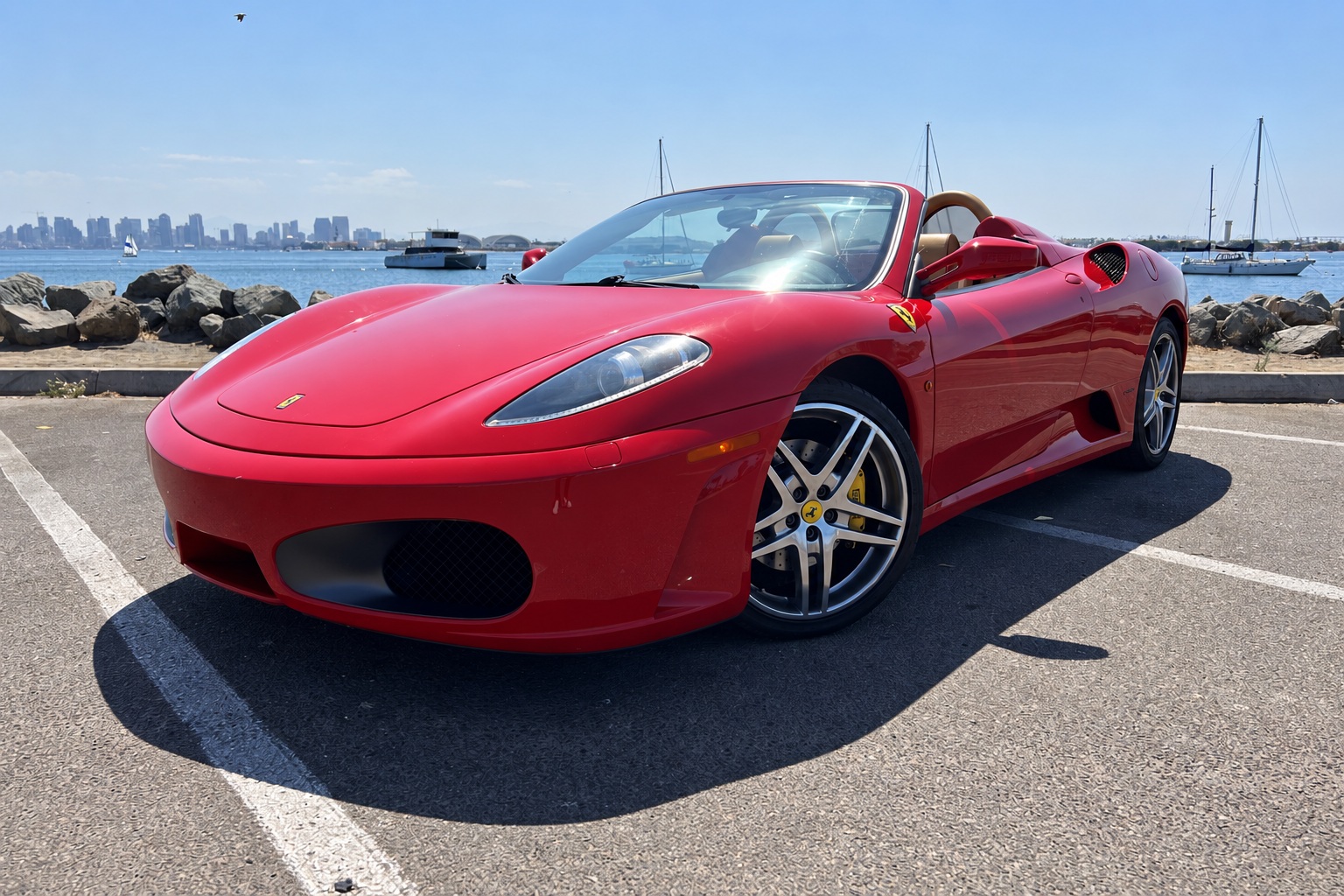 Red Ferrari F430 Spider with the roof down, front three-quarter view, shield on the fender and yellow calipers