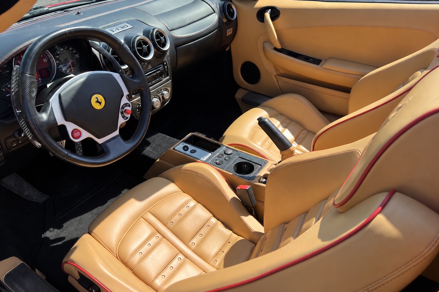 Driver's view of the Ferrari F430 Spider cabin, tan leather, the manettino on the wheel and the yellow shield