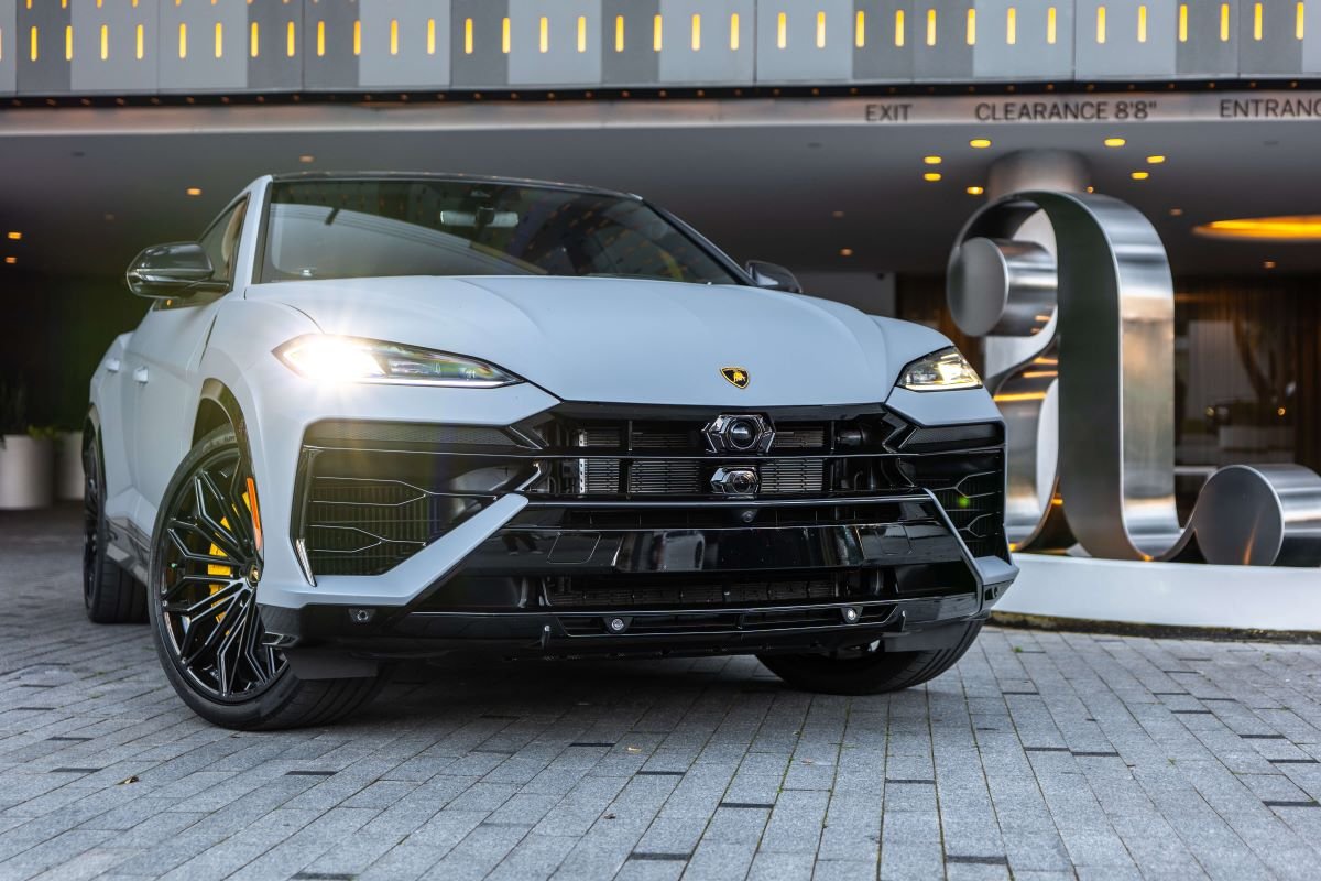 Head-on view of the grey Urus SE under the portico, black wheels, yellow calipers and the floating hood line