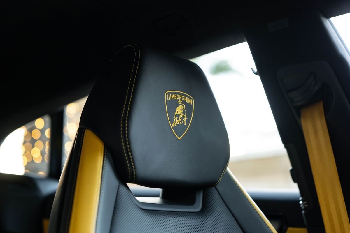 Front headrest of the Urus SE with the Lamborghini shield embroidered and the yellow seat belt