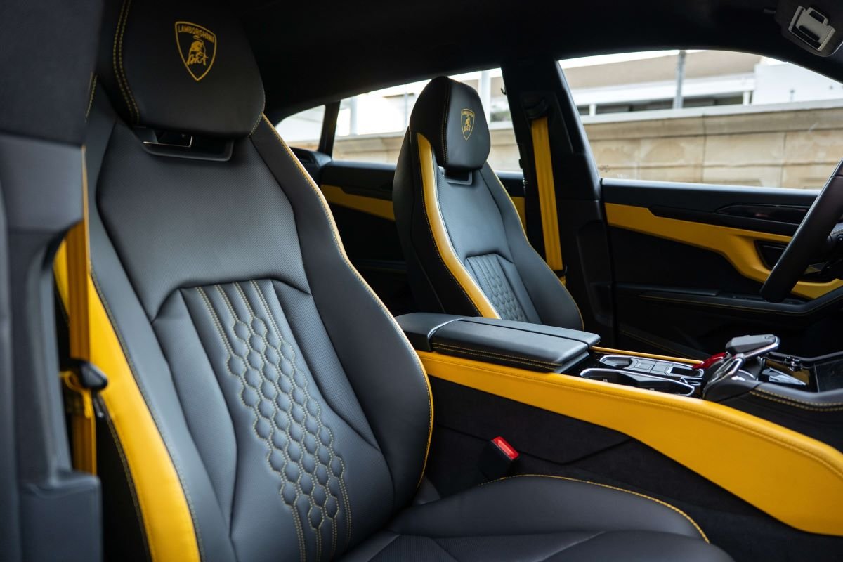 Front seats of the Urus SE from the passenger side, quilted black leather and yellow trim on the console