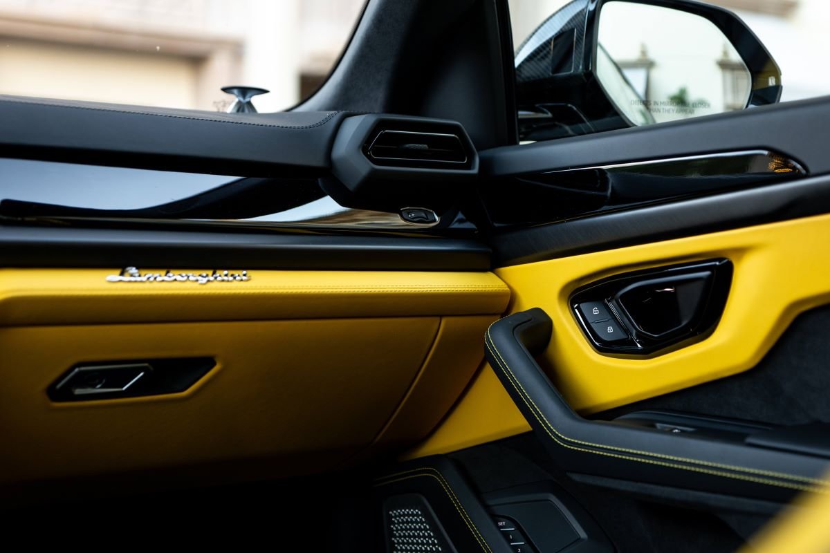 Inside of the Urus SE door with the yellow leather panel, Lamborghini script and the speaker grille