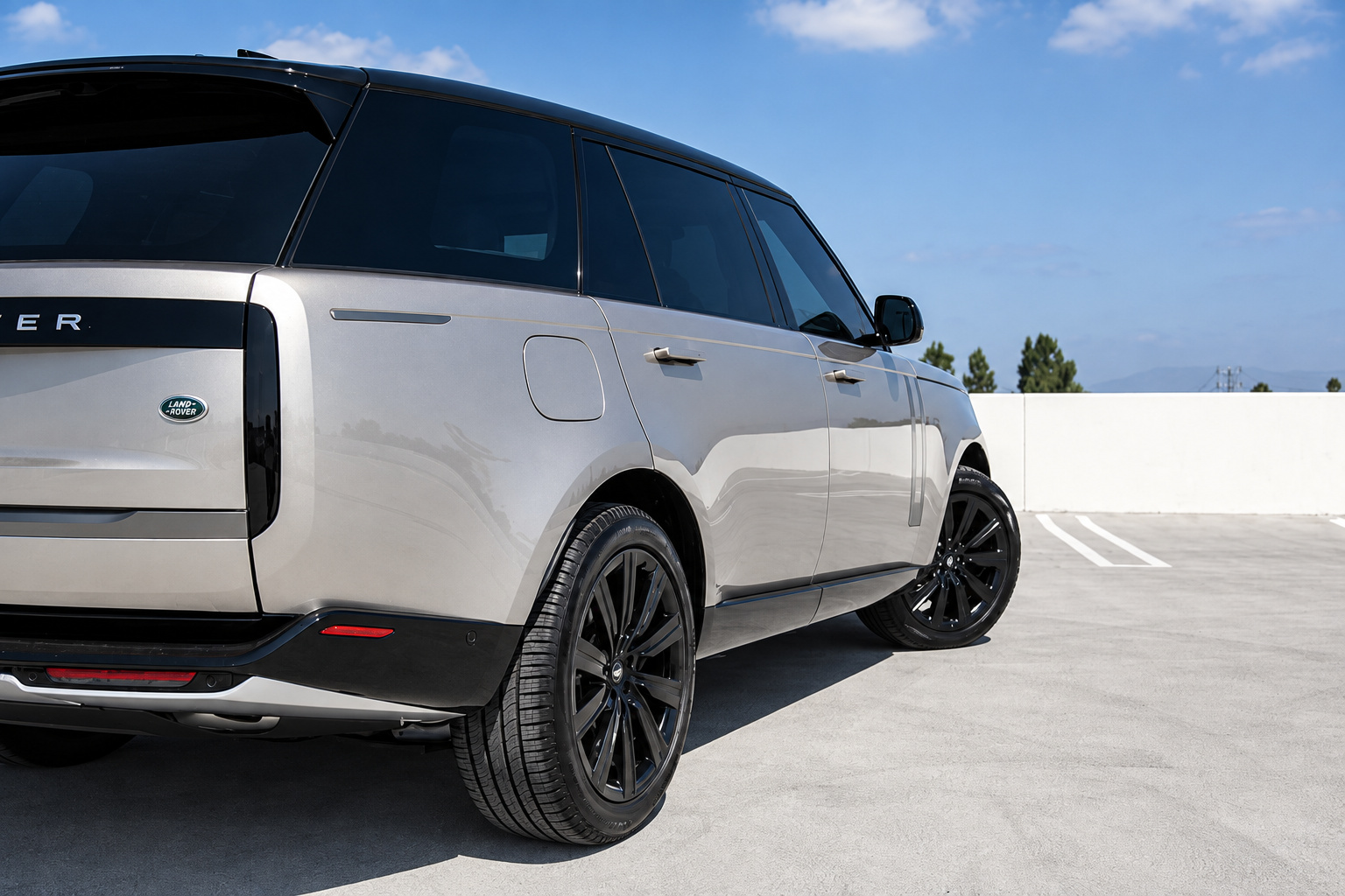 Rear three-quarter of the champagne Range Rover HSE, black wheel, split tailgate and Land Rover badge