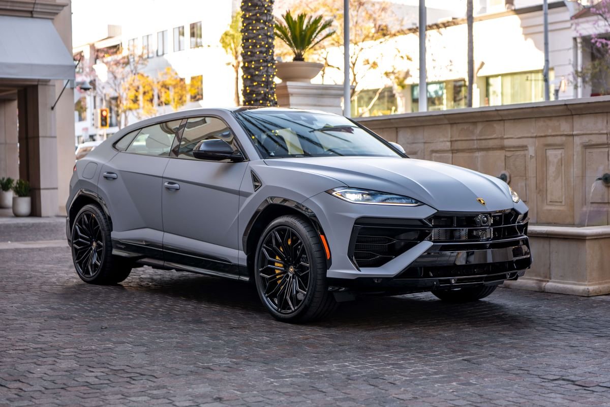Grey Urus SE on cobbles in a Beverly Hills courtyard, front three-quarter with palms and the hotel behind