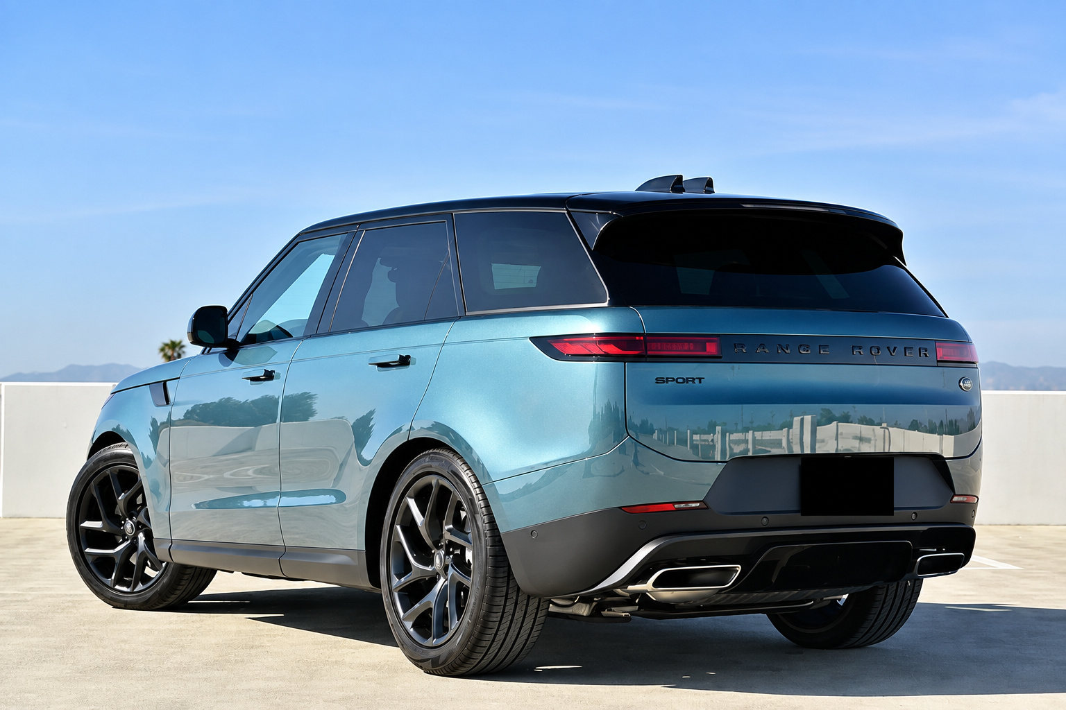 Light blue Range Rover Sport with black wheels and black roof, rear three-quarter view on a rooftop deck