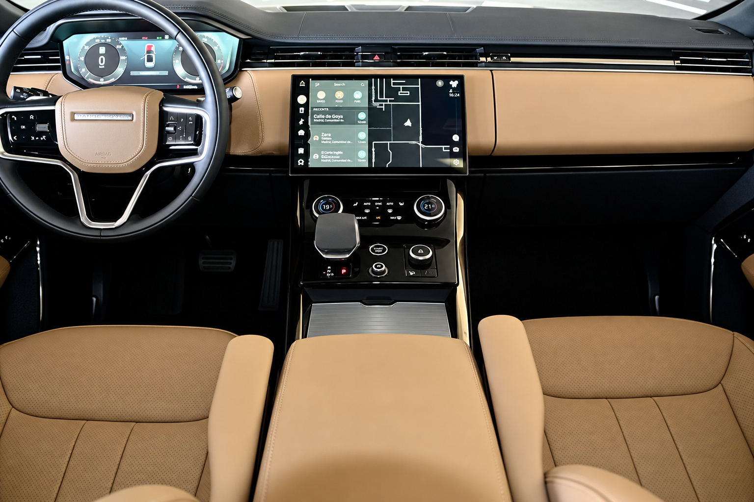 Caramel tan leather dash and seats of the Range Rover Sport with the floating touchscreen and steering wheel