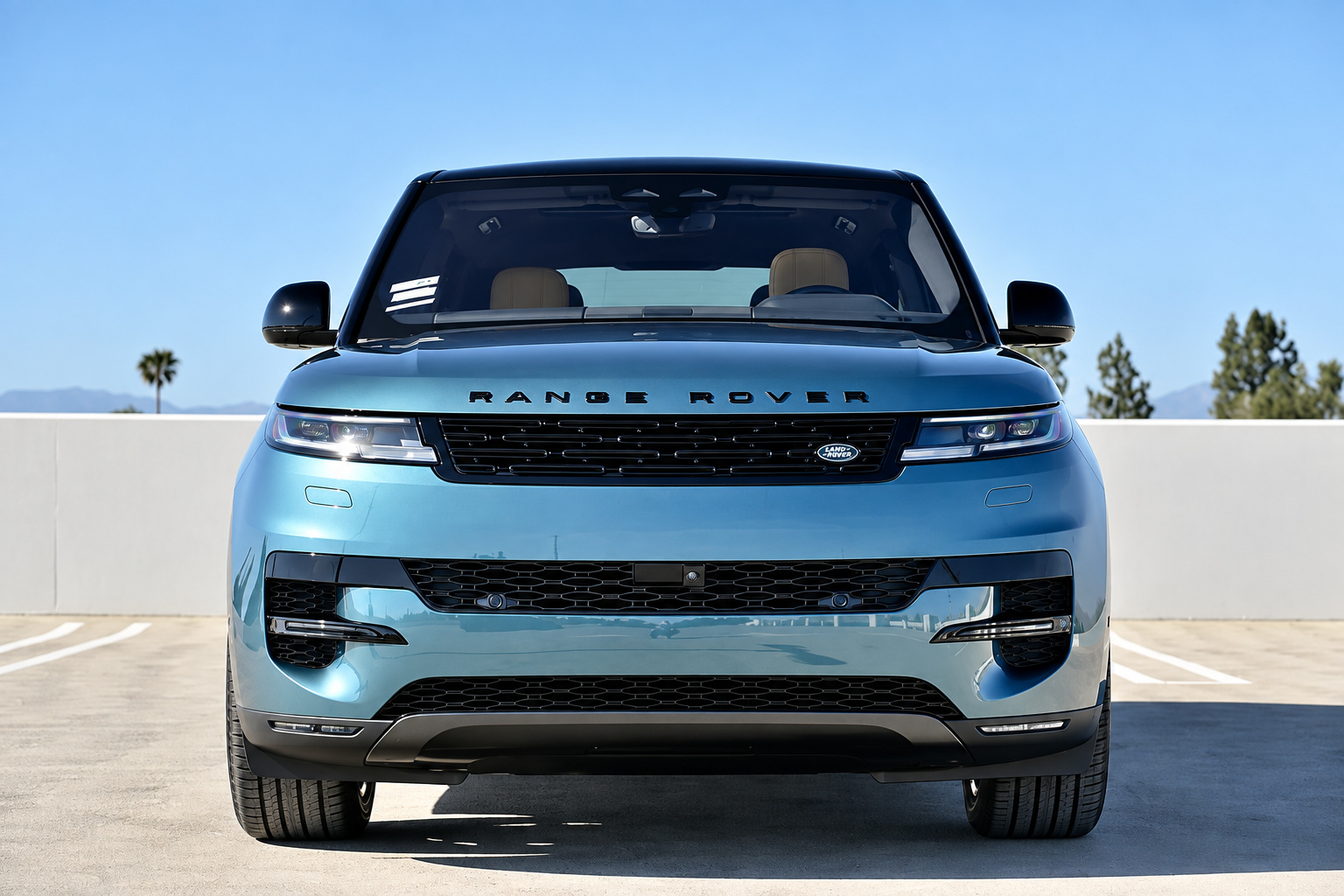 Head-on view of the light blue Range Rover Sport on a rooftop deck with mountains in the distance