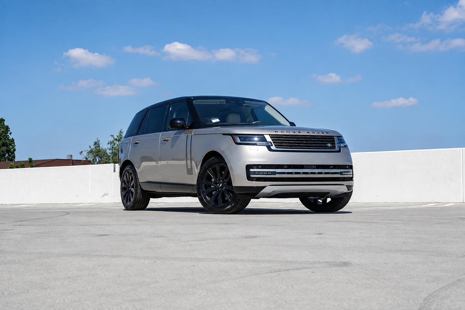 Champagne Range Rover HSE with black roof and black 22-inch wheels, front three-quarter on a rooftop deck