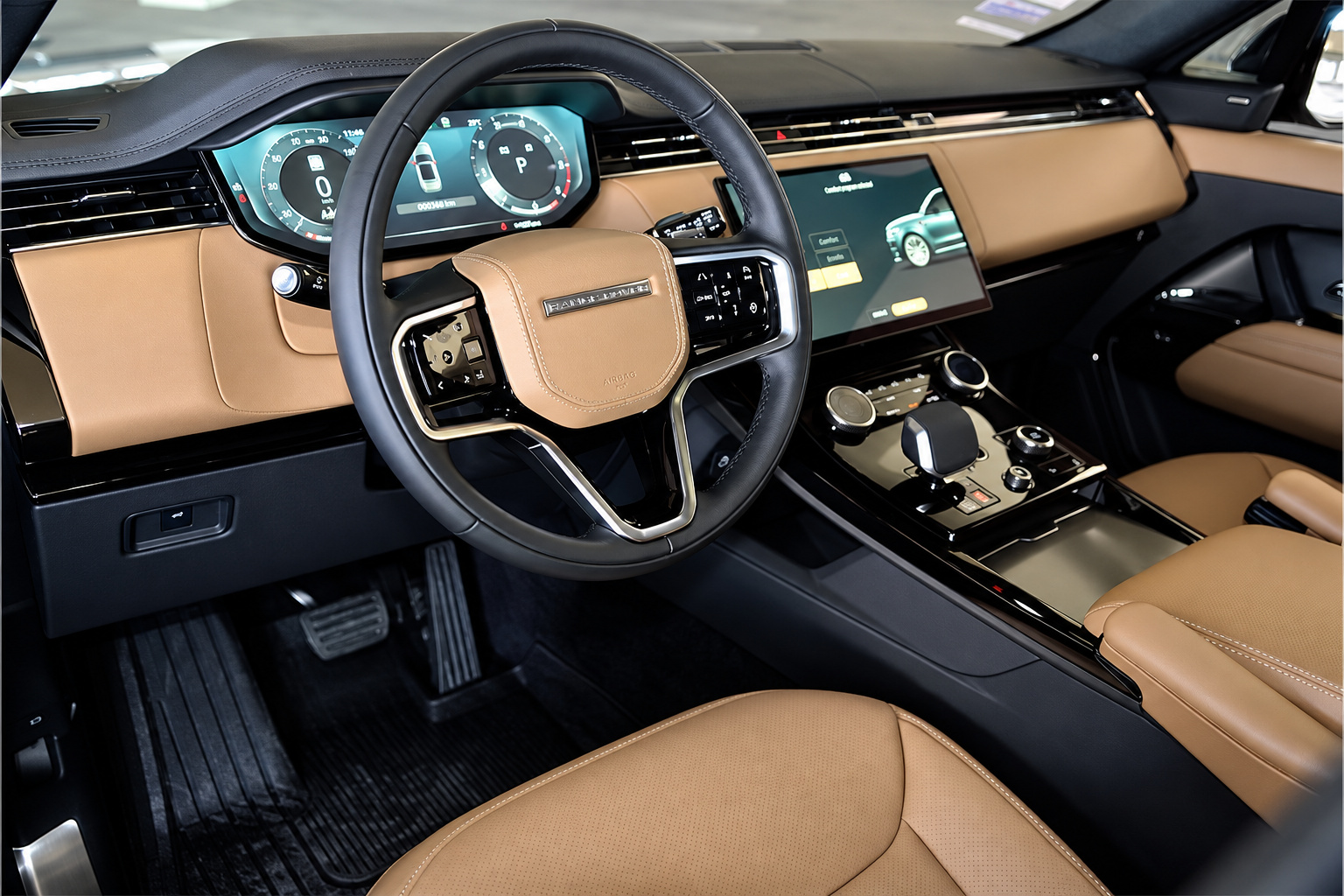 Driver's side of the Range Rover Sport cabin, tan leather, digital cluster and the steering wheel